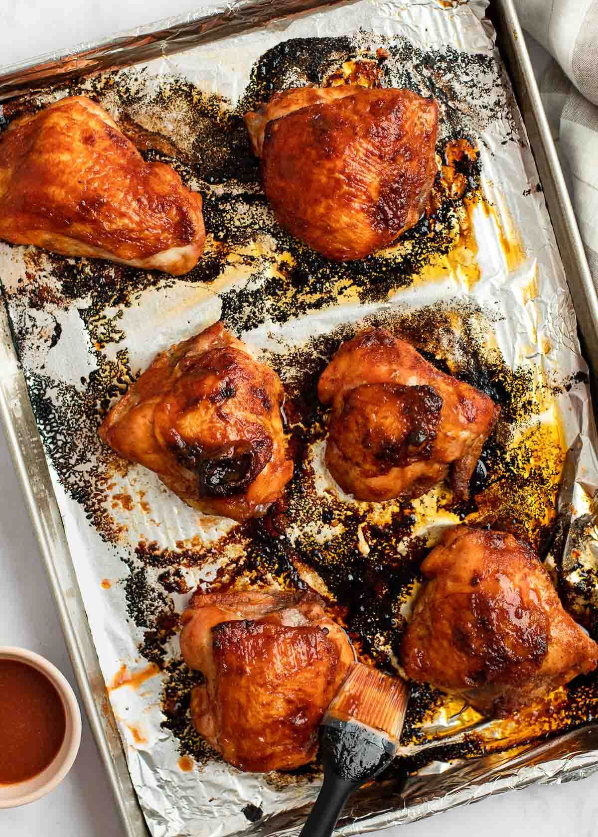 baked bbq chicken thighs on a baking pan lined with aluminum foil