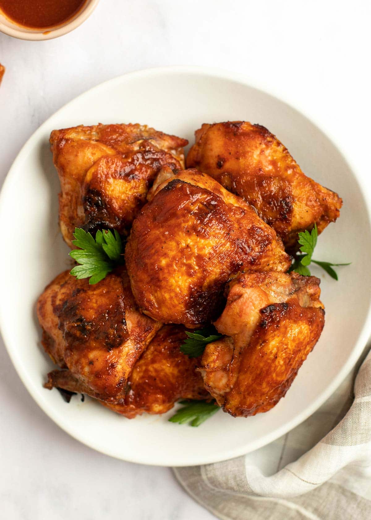 baked bbq chicken thighs on a white serving plate with parsley