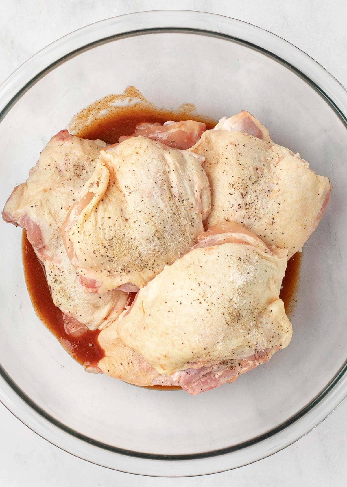 chicken thighs in a glass bowl of marinade