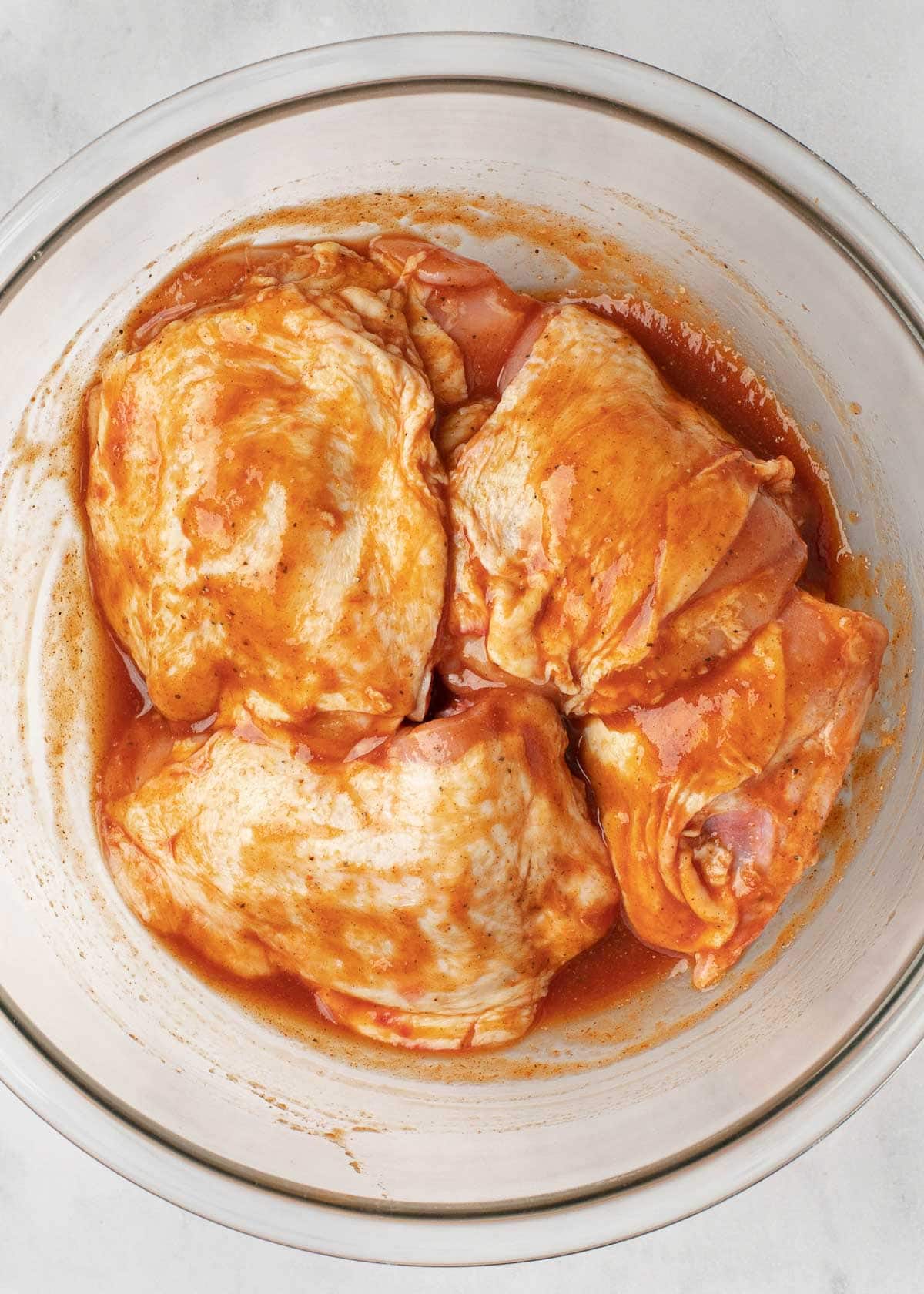 chicken thighs covered in marinade in glass bowl