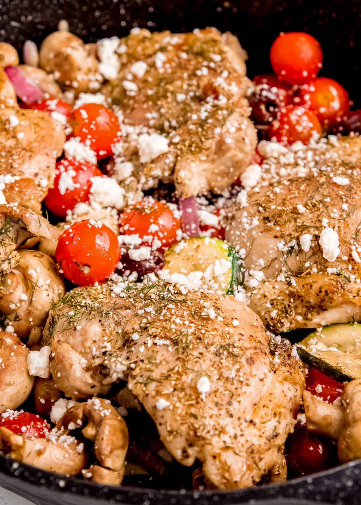 closeup of chicken thighs and vegetables in cast iron skillet