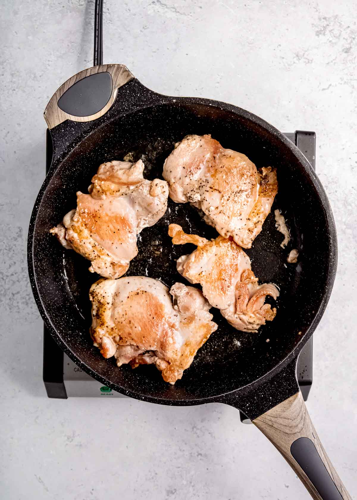 chicken chicken thighs browning in cast iron pan