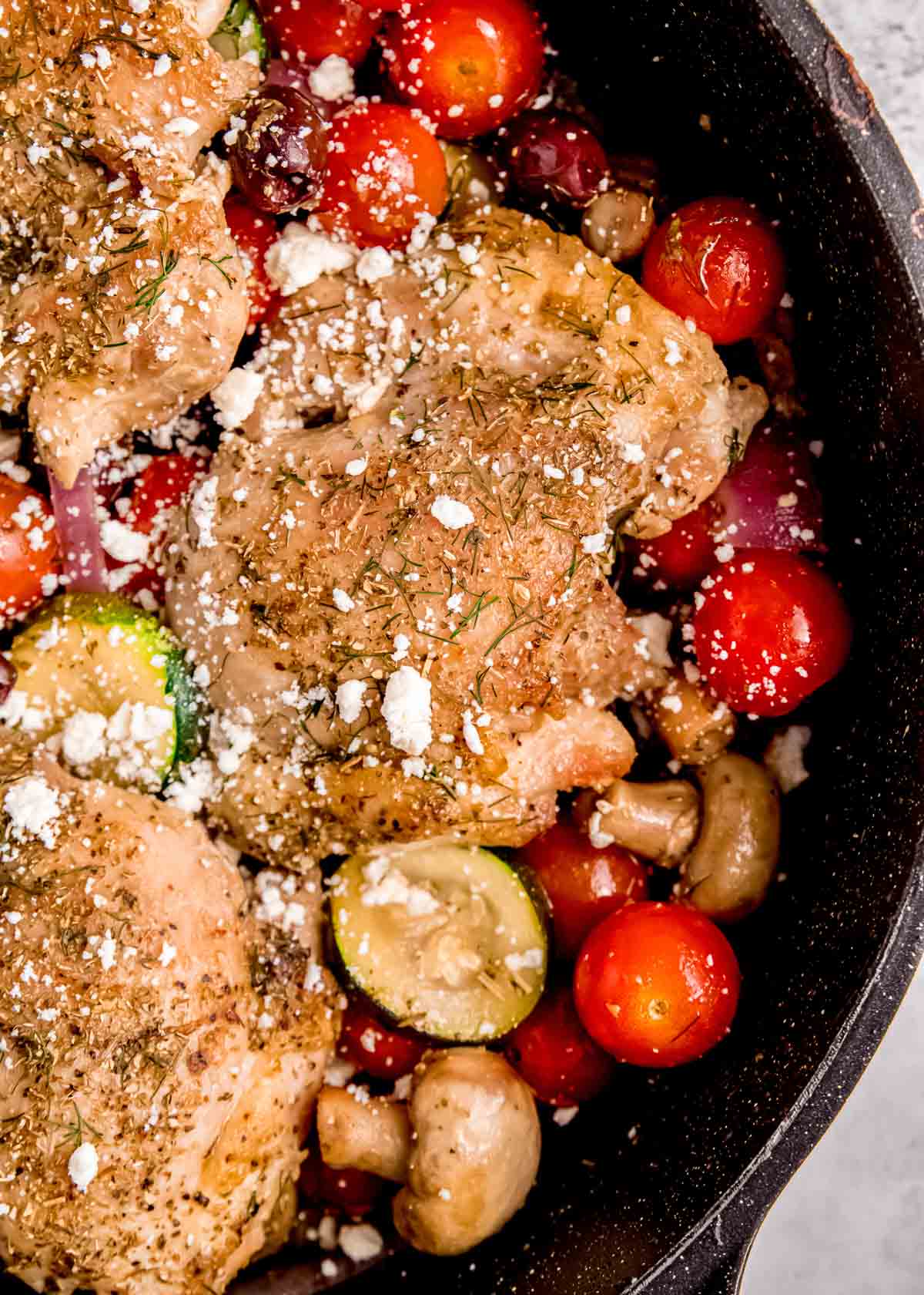 juicy chicken thighs, tomatoes, zucchini, mushrooms, onion, and feta in a skillet