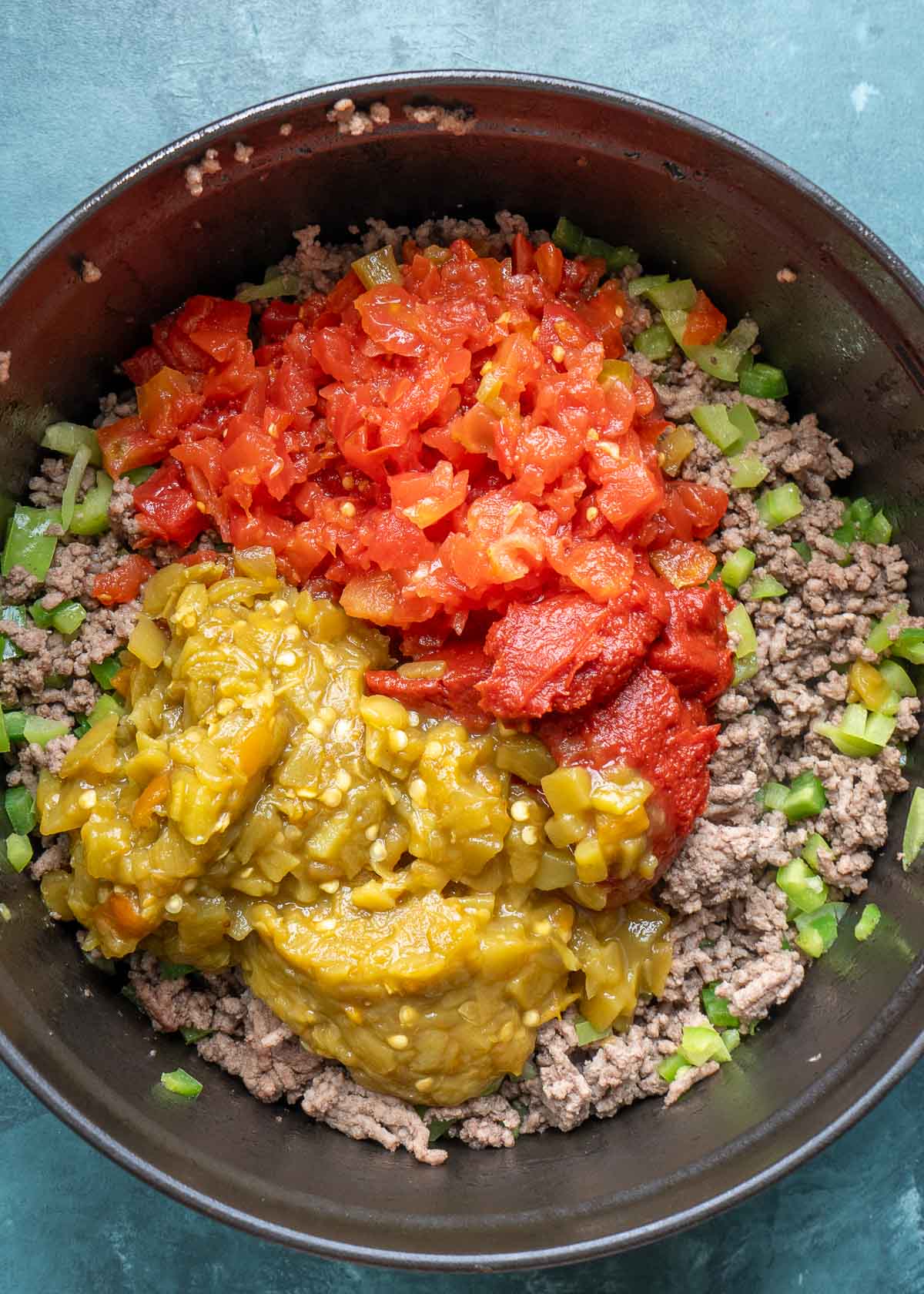 browned ground beef, jalapenos, bell peppers, tomatoes, green chilies, taco seasoning, and tomato paste in a dutch oven