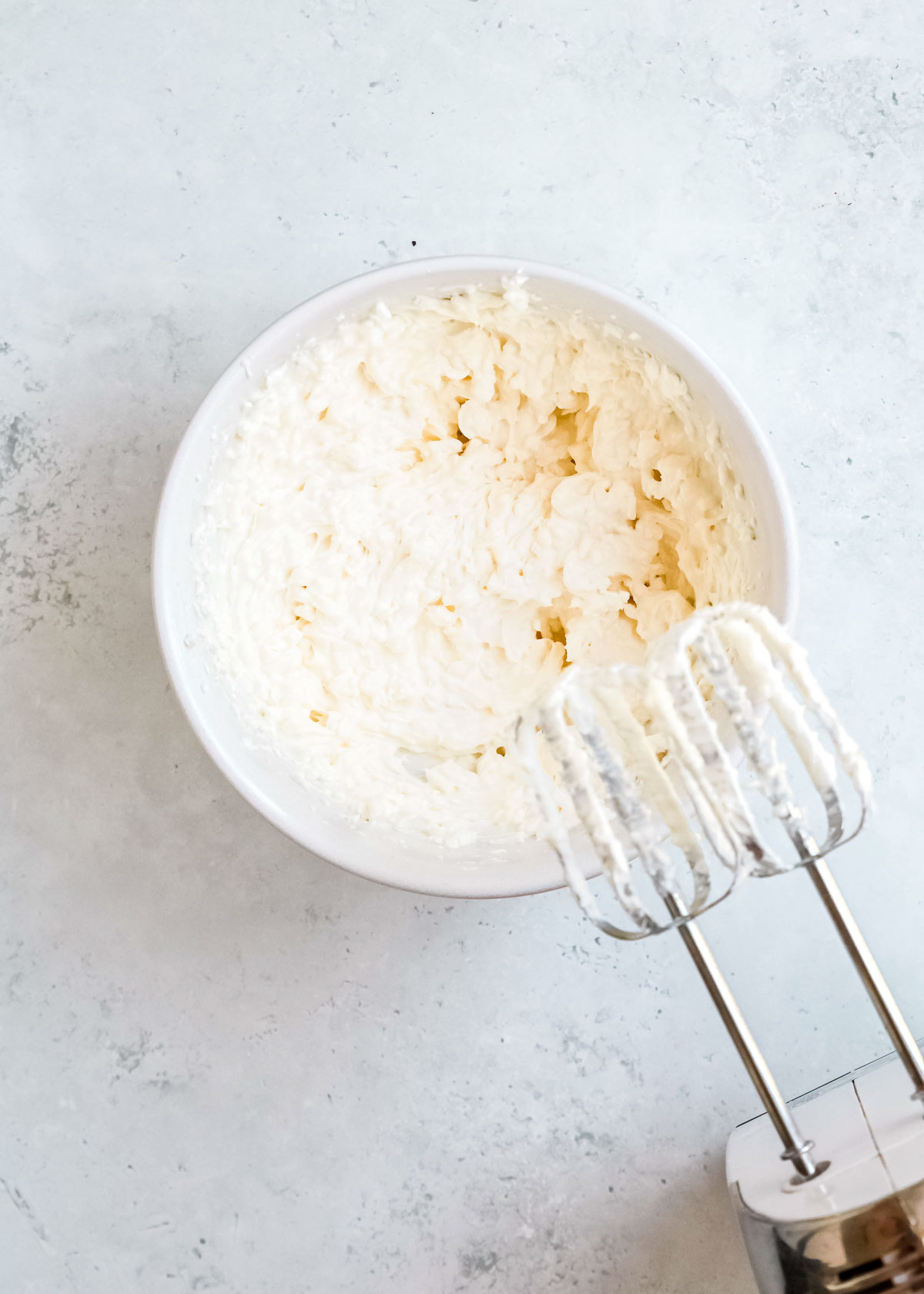an electric mixer dirtied with creamed yogurt, cream cheese, and mayonnaise