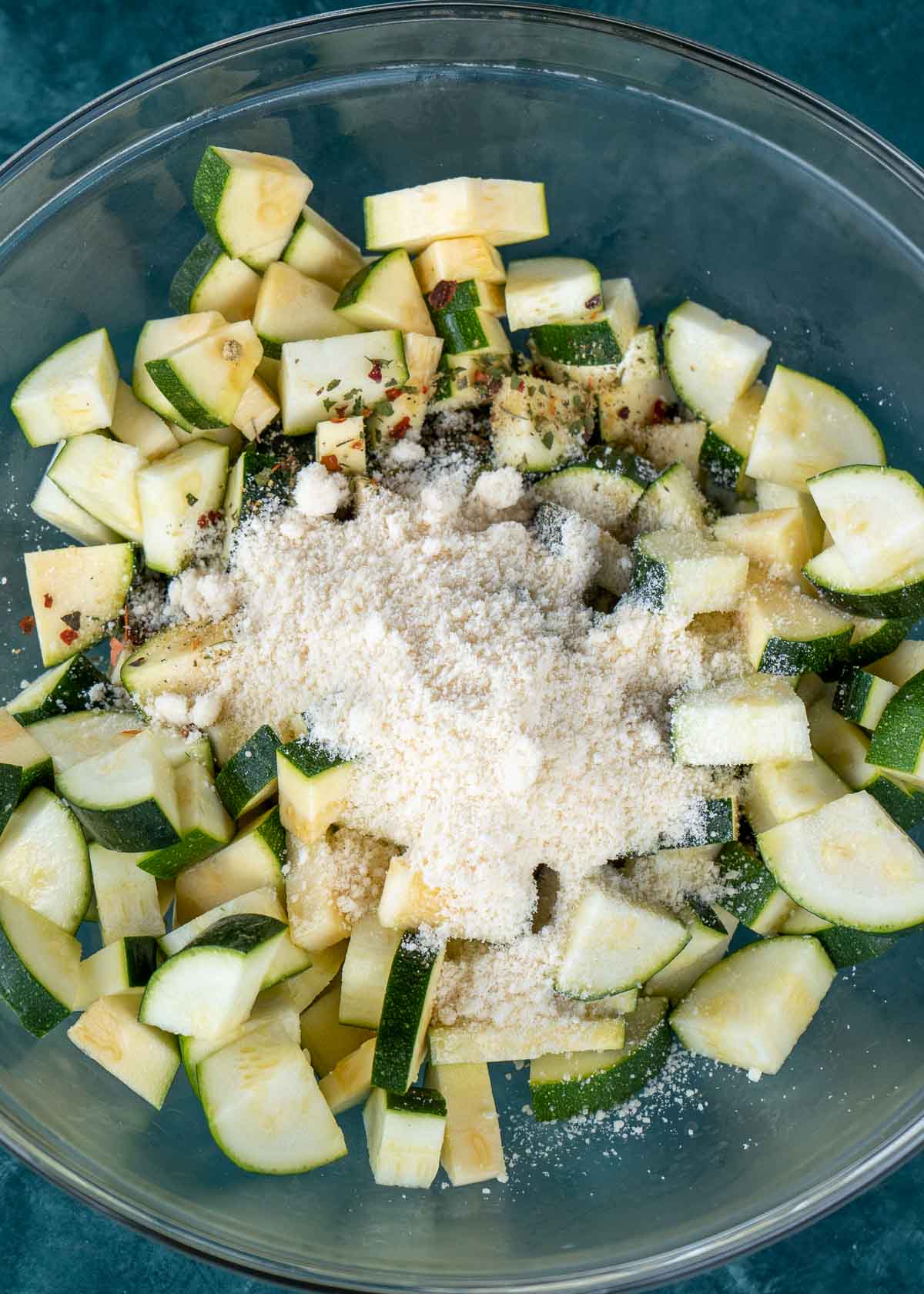 chopped zucchini with seasonings and parmesan in a glass bowl