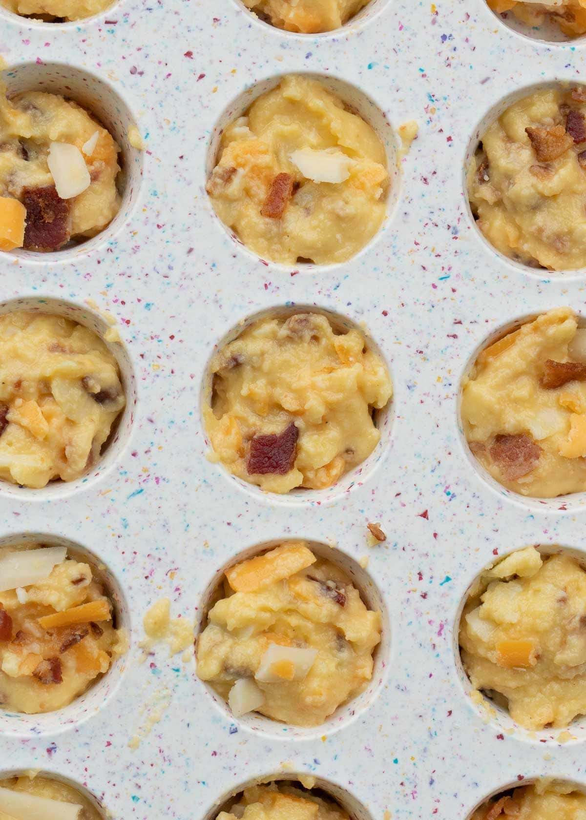 uncooked egg bite mixture in mini muffin pan, overhead shot