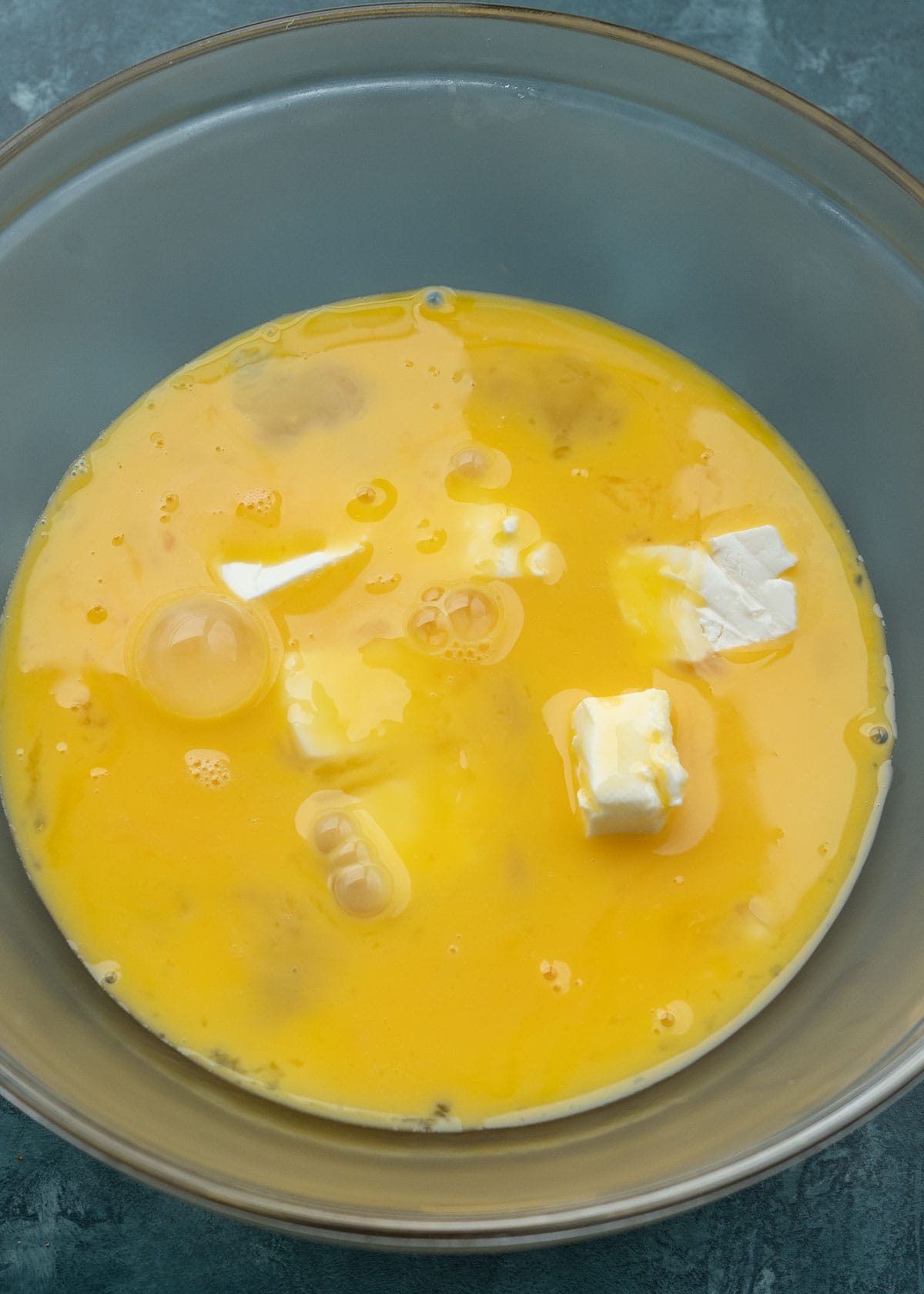 egg and pieces of softened cream cheese in a glass bowl