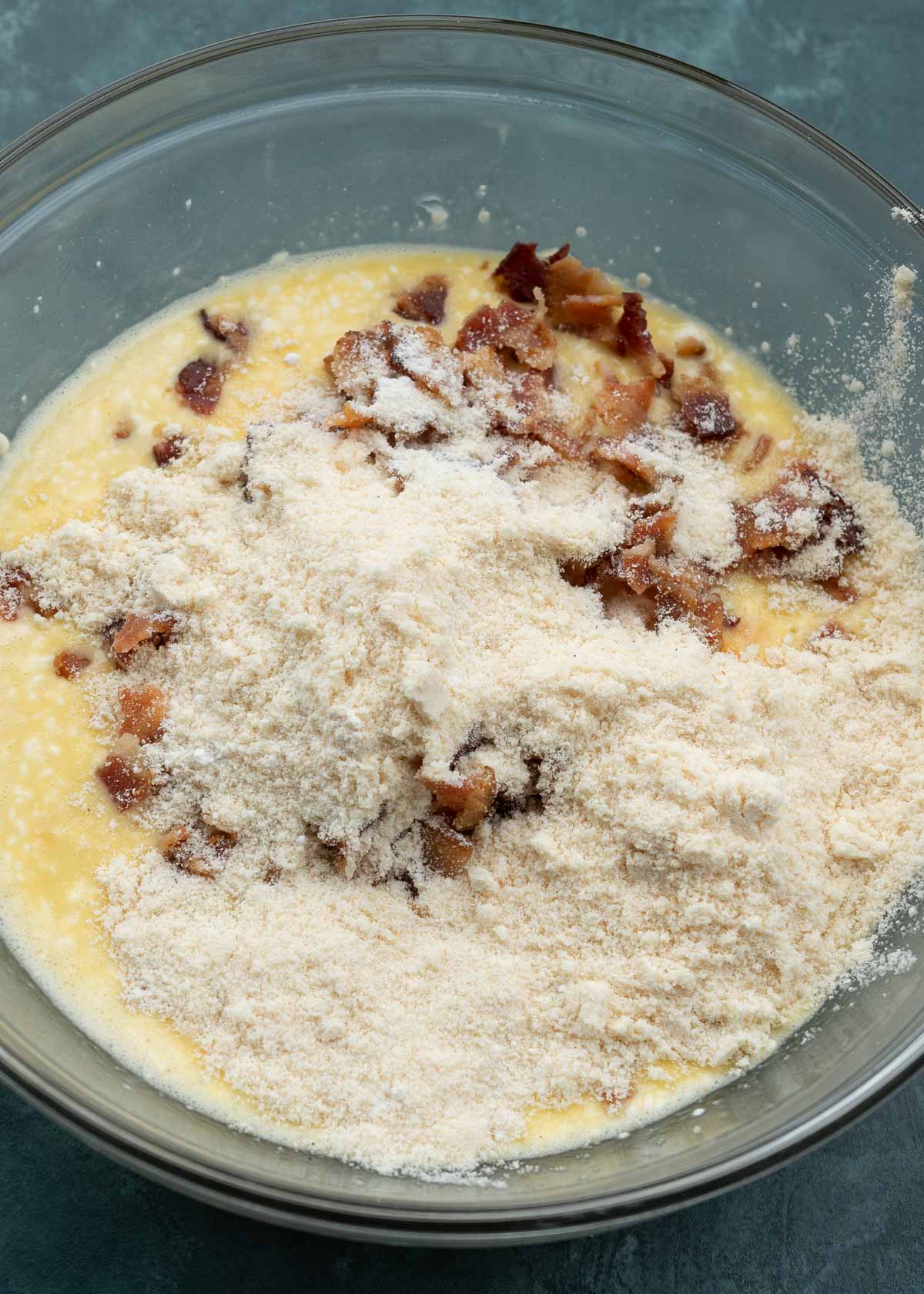 eggs, cream cheese, shredded cheese, bacon, flour, and baking powder in a glass bowl
