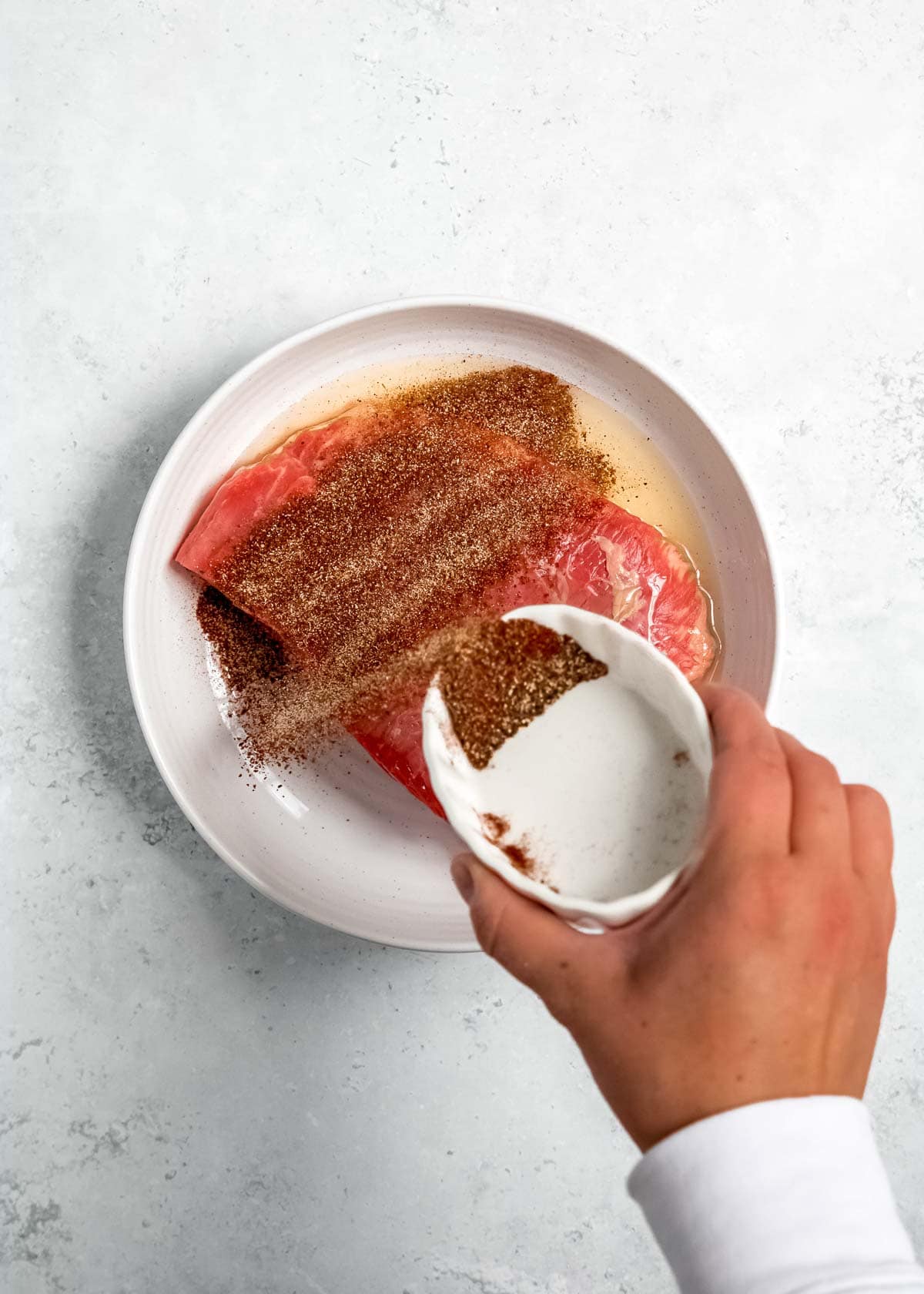 marinade being added to steak on white plate