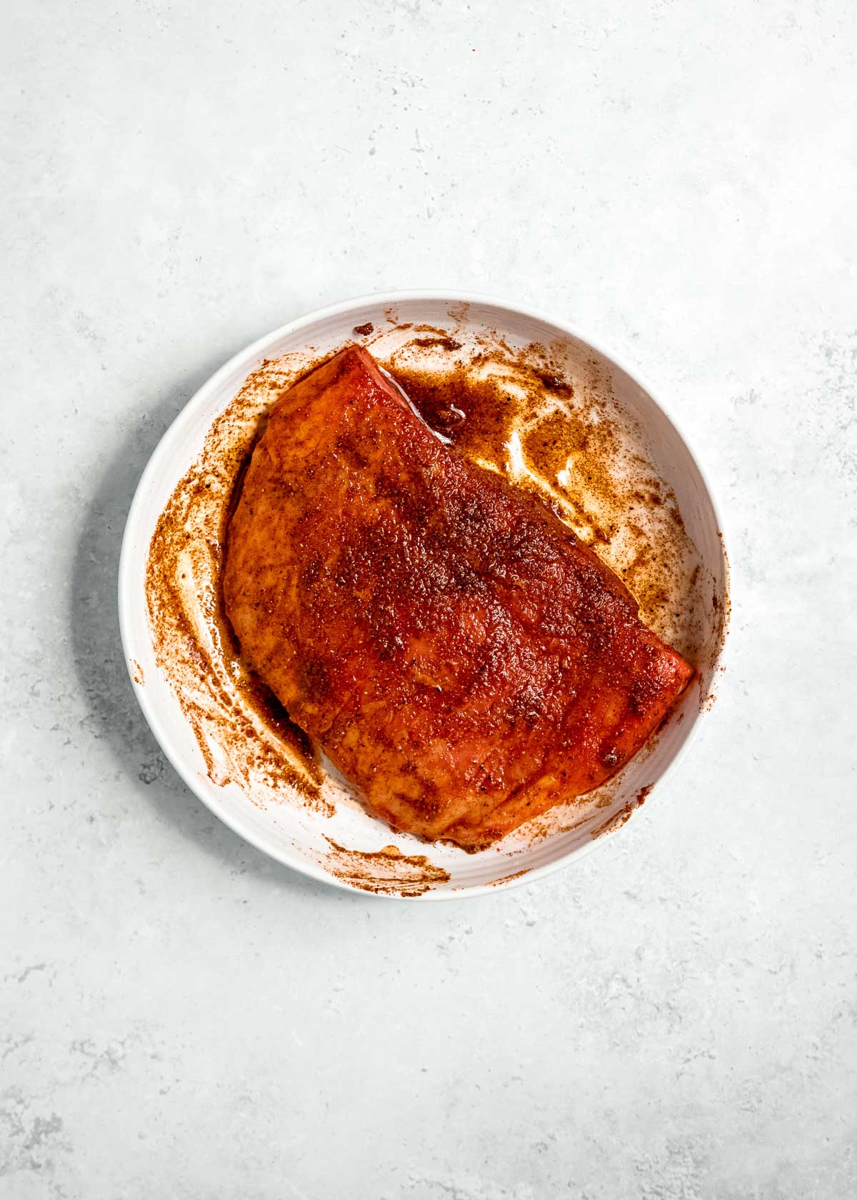 marinade being added to steak on white plate