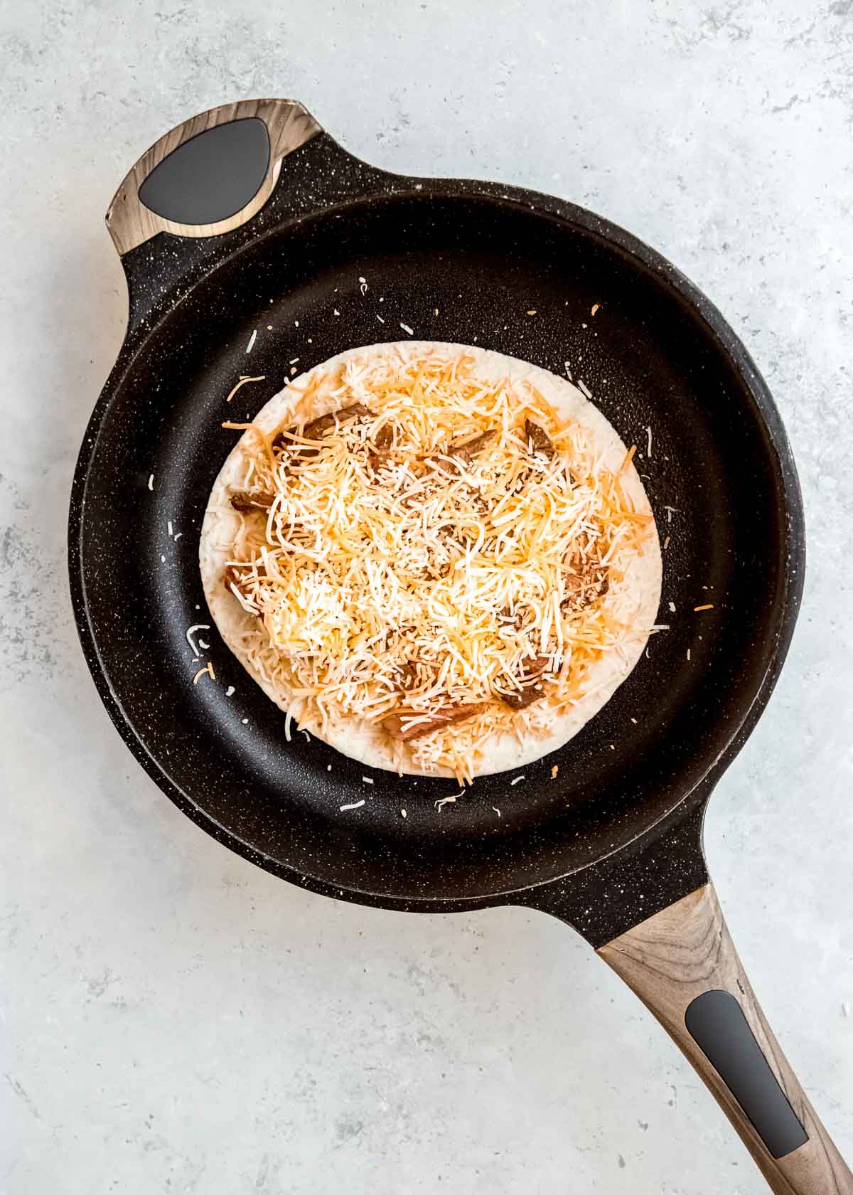 steak quesadilla in skillet prior to topping with second tortilla 