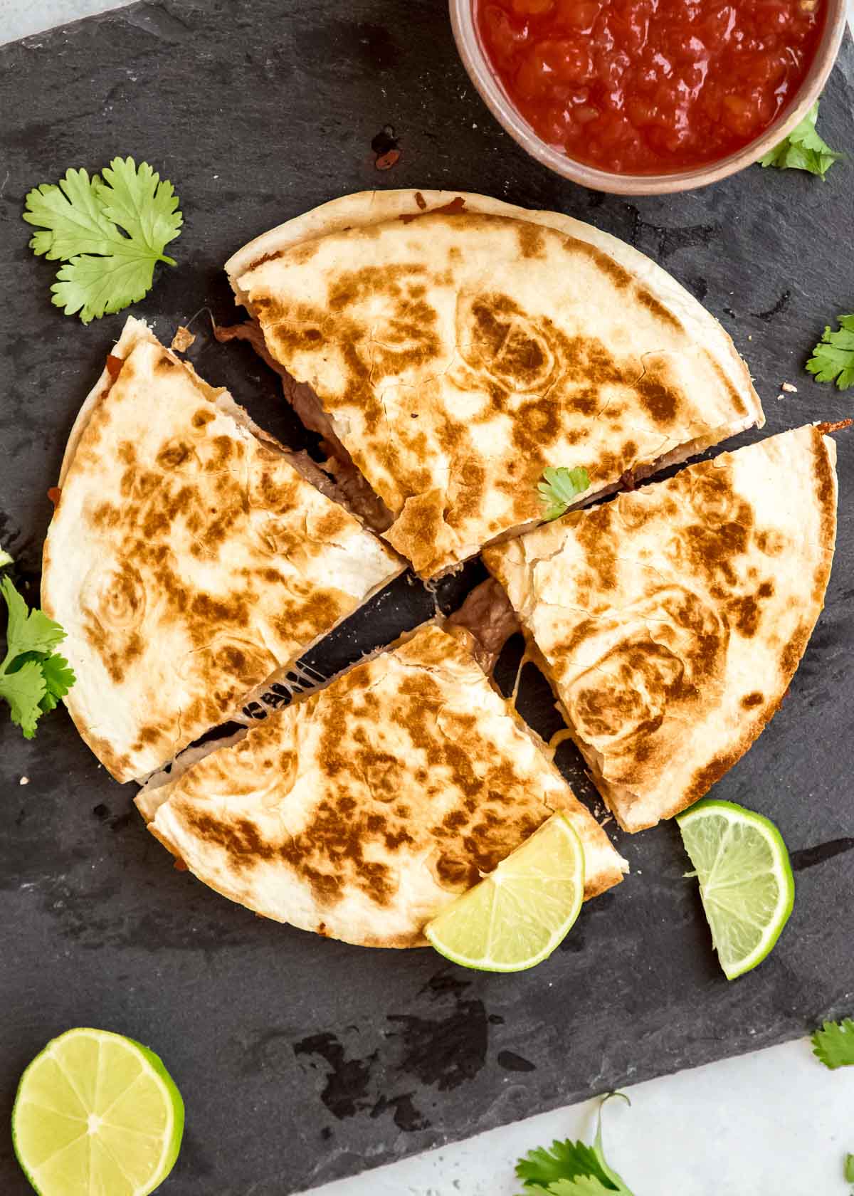 steak quesadilla cut into 4 sections on gray background