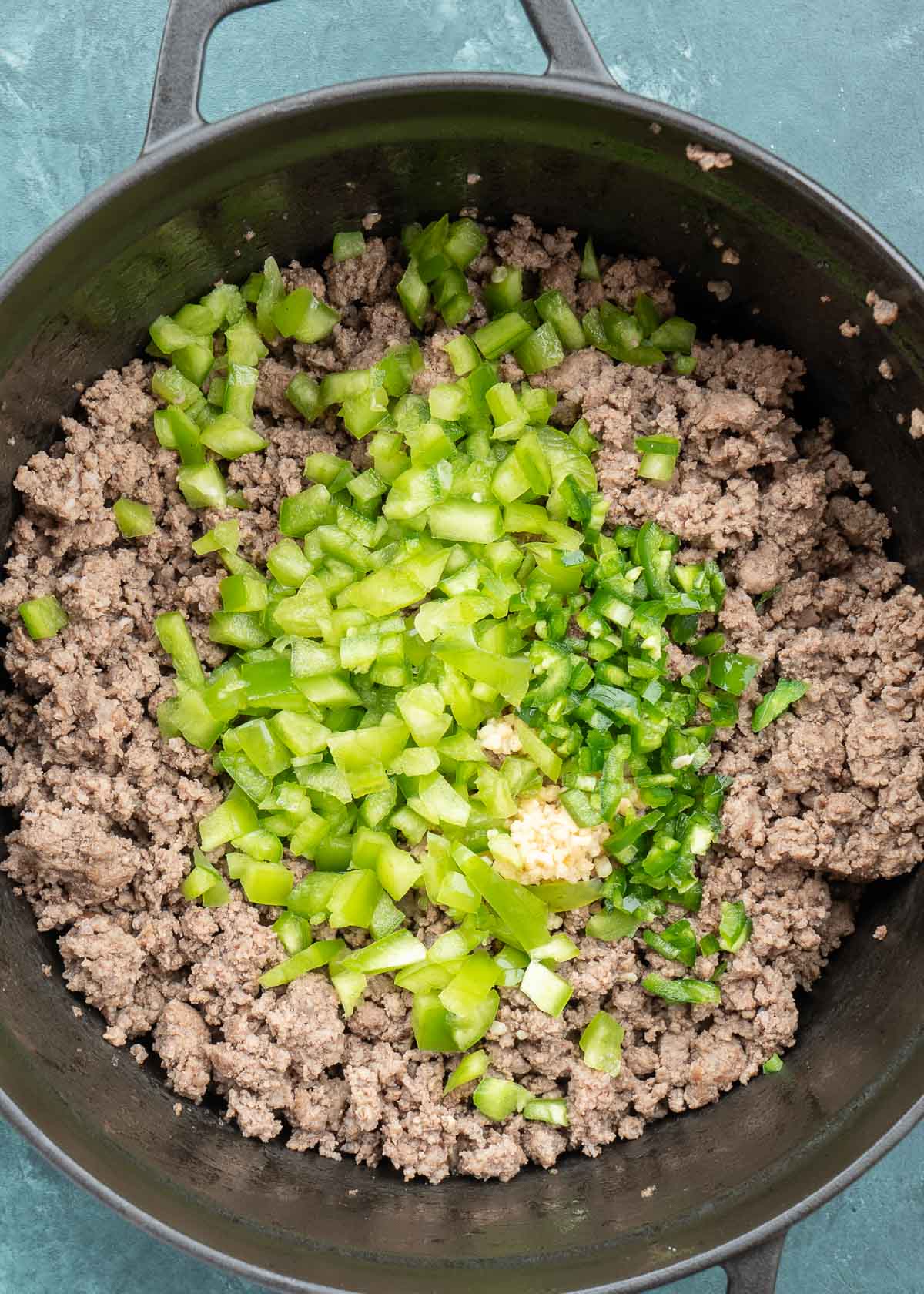 ground beef, peppers and garlic in dutch oven