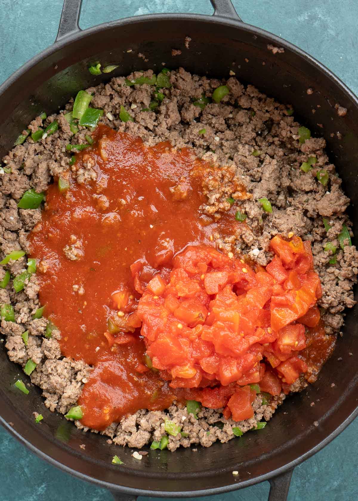 ground beef, peppers, tomato sauce and canned tomatoes in dutch oven