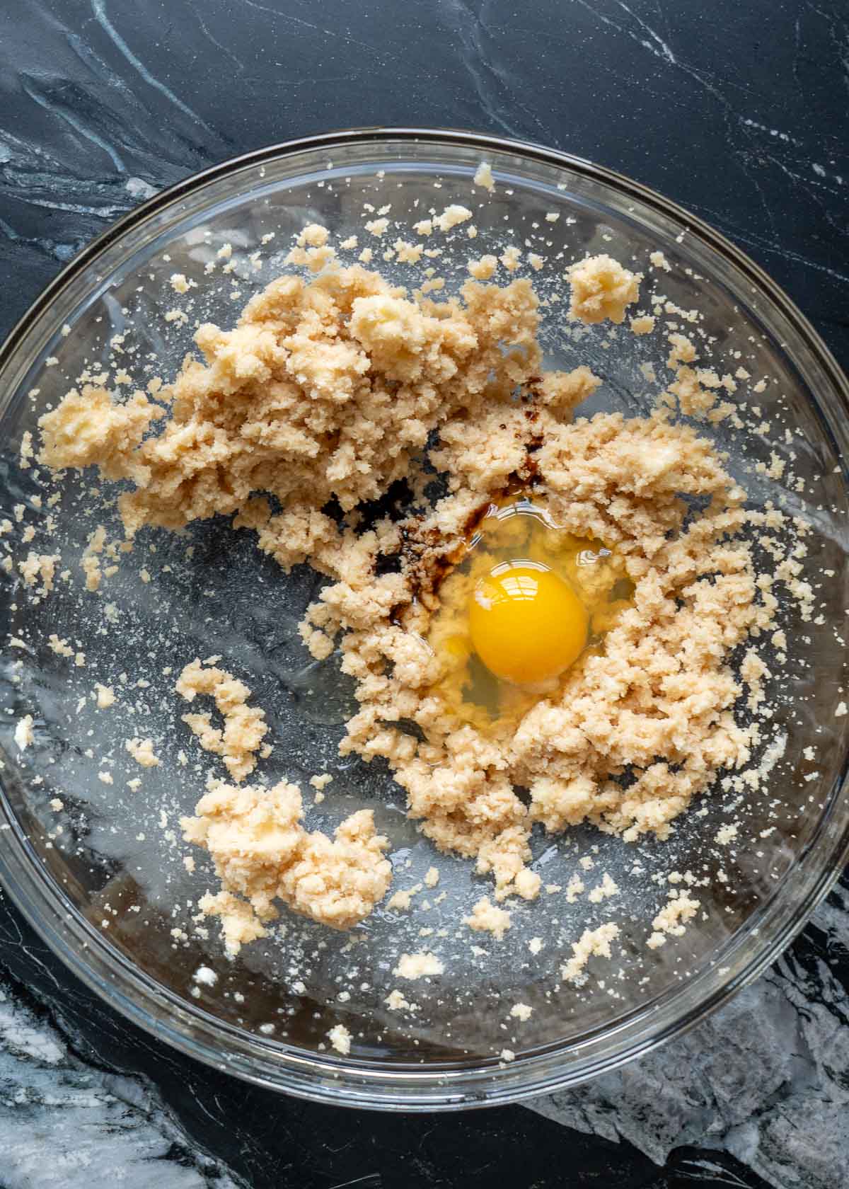 raw egg on a butter and brown sugar monk fruit mixture in a stand mixer bowl