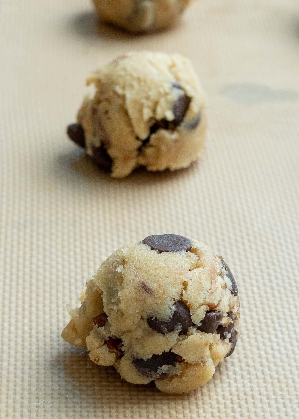 gluten free chocolate chip cookie dough scooped and placed on a silicone lined baking sheet