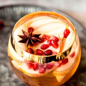 apple cider sangria in cup with pomegranate seeds and apple slices