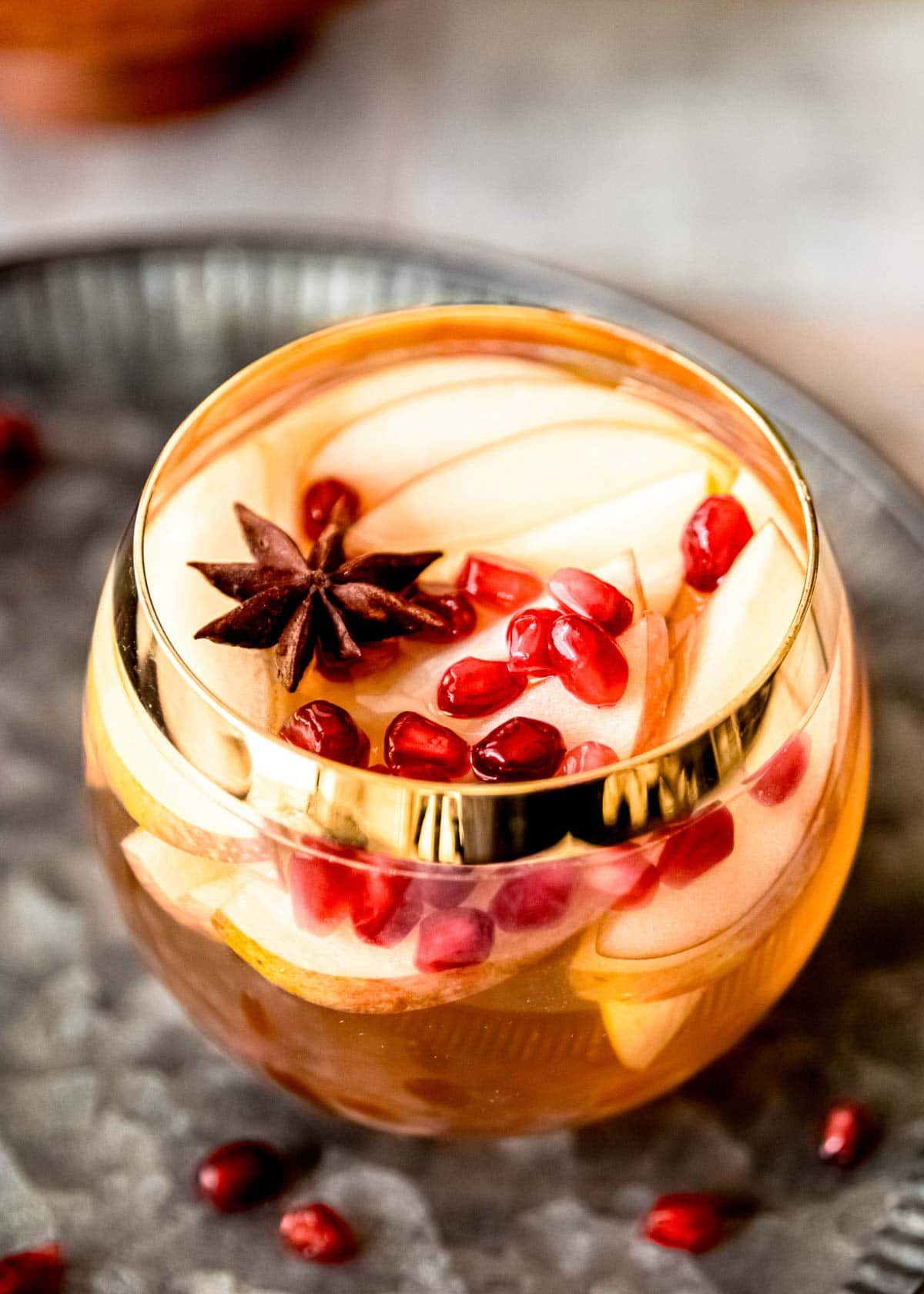 apple cider sangria in cup with pomegranate seeds and apple slices