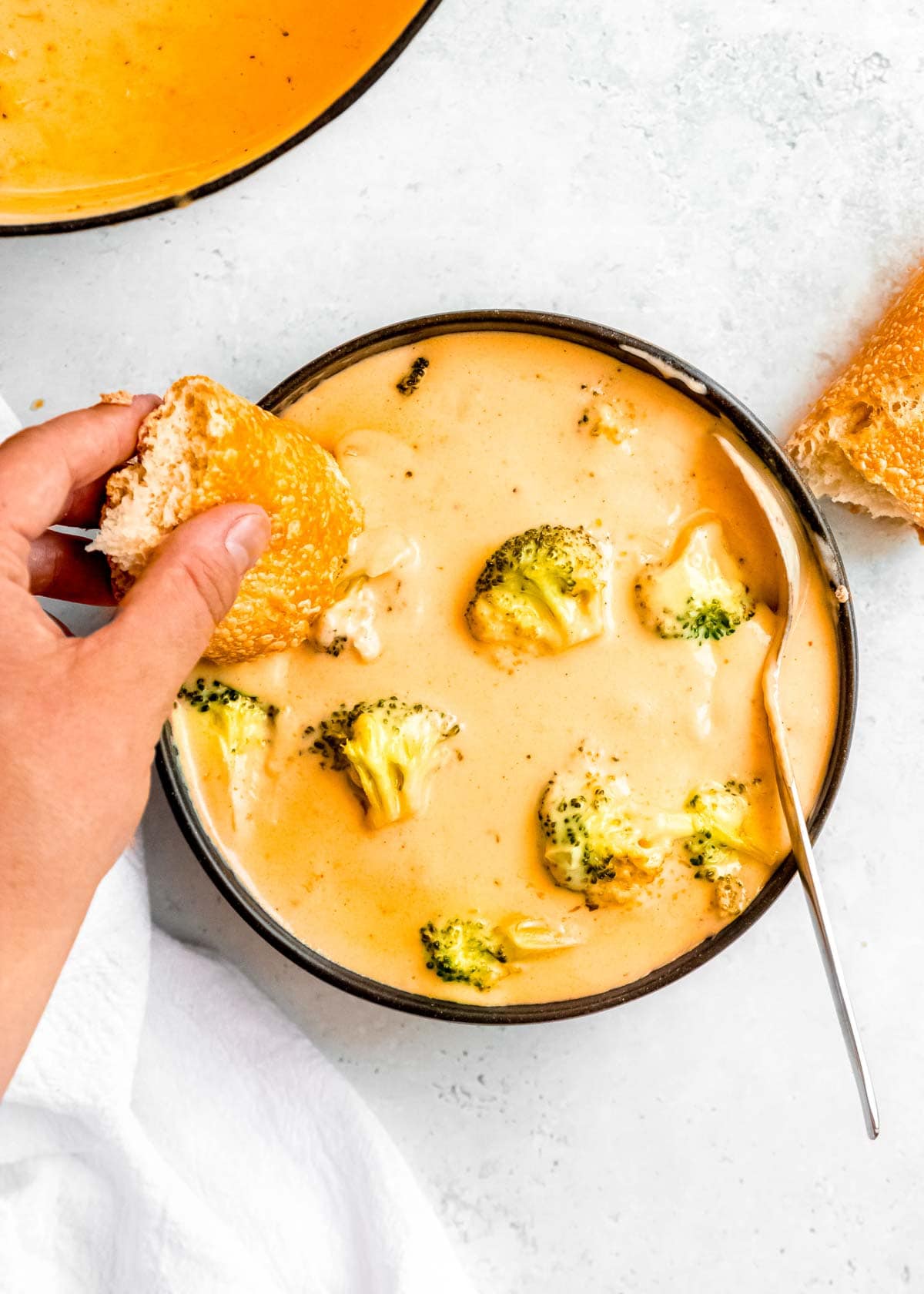 overhead shot of broccoli cheddar soup with a spoon and bread