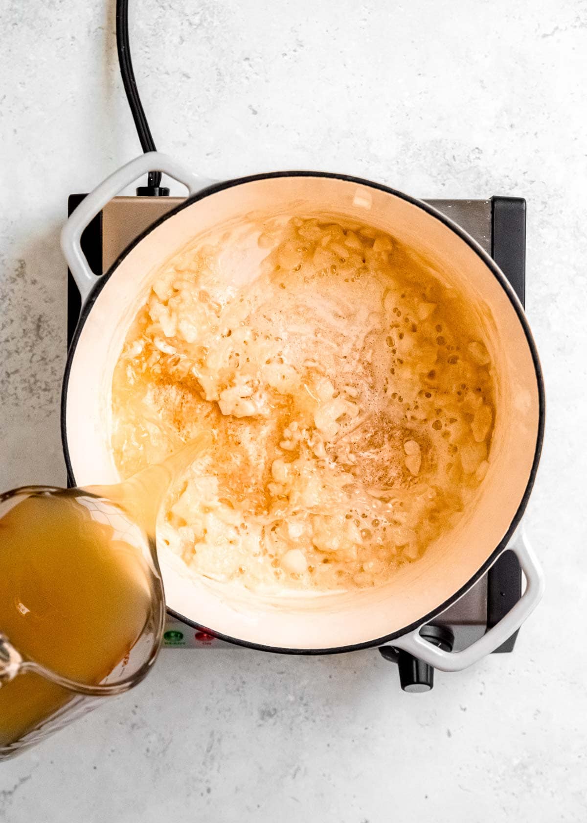 broth being poured into a dutch oven