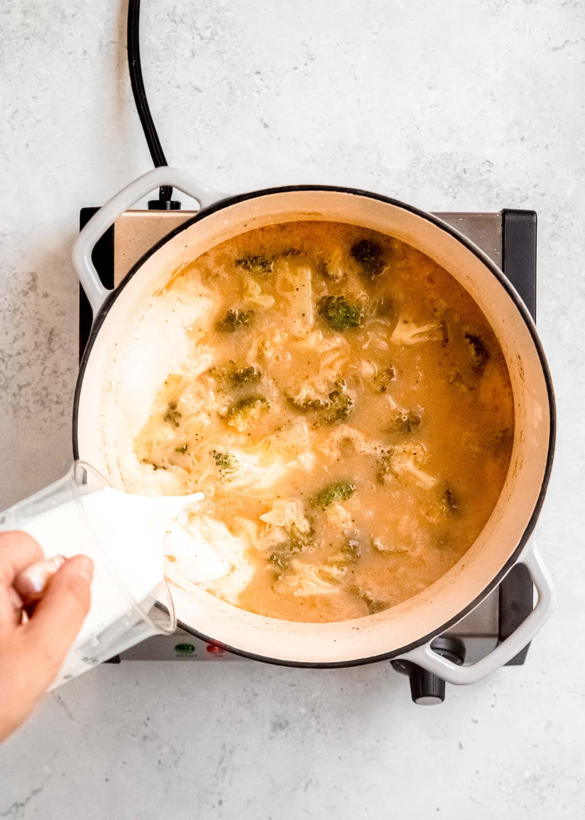 half and half being poured into a dutch oven