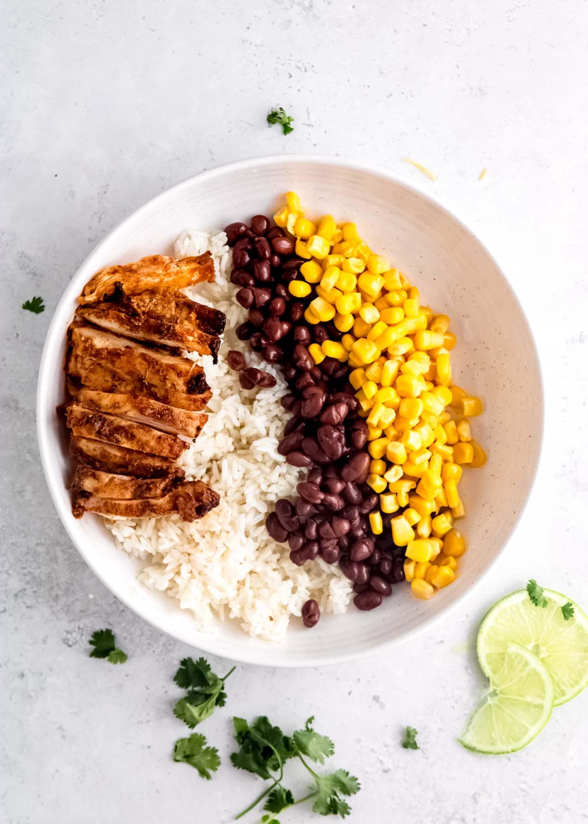 chicken, rice, beans and corn on a white plate