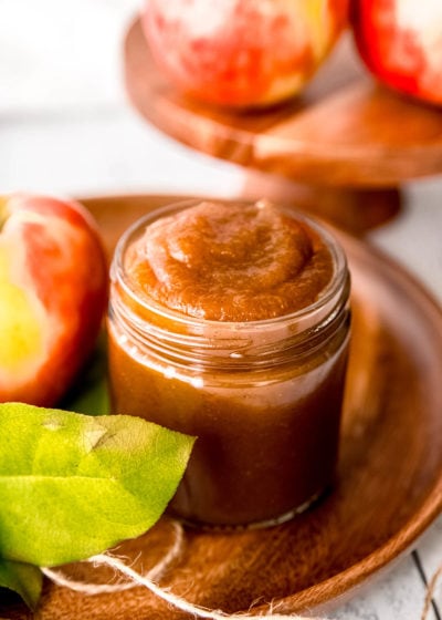 apple butter in a jar on a plate with apples
