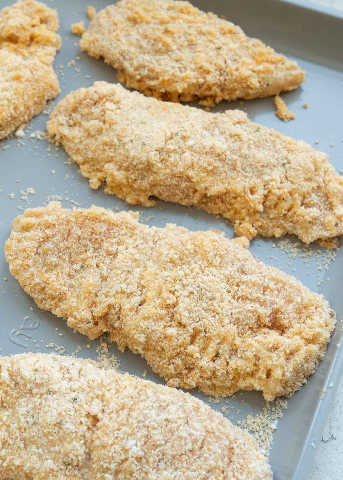 breaded chicken tenders on greased baking sheet