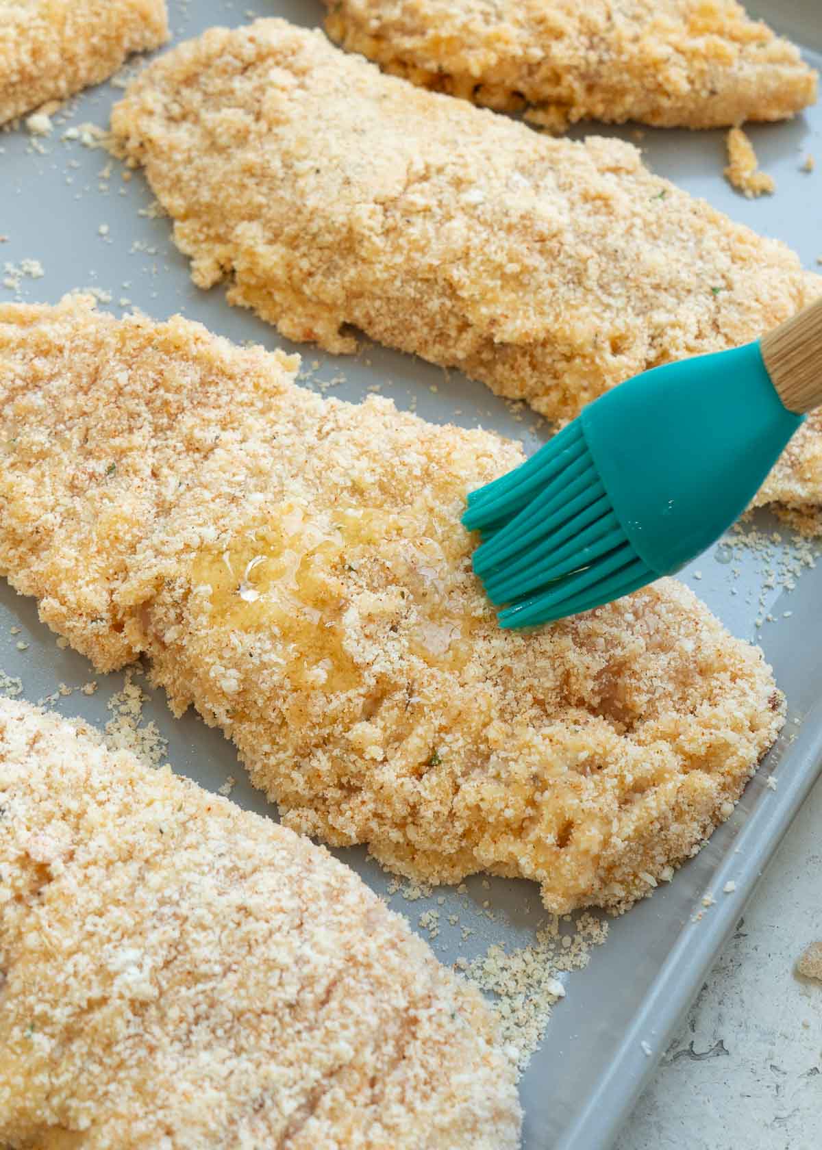 butter being brushed on chicken tenders with silicone brush