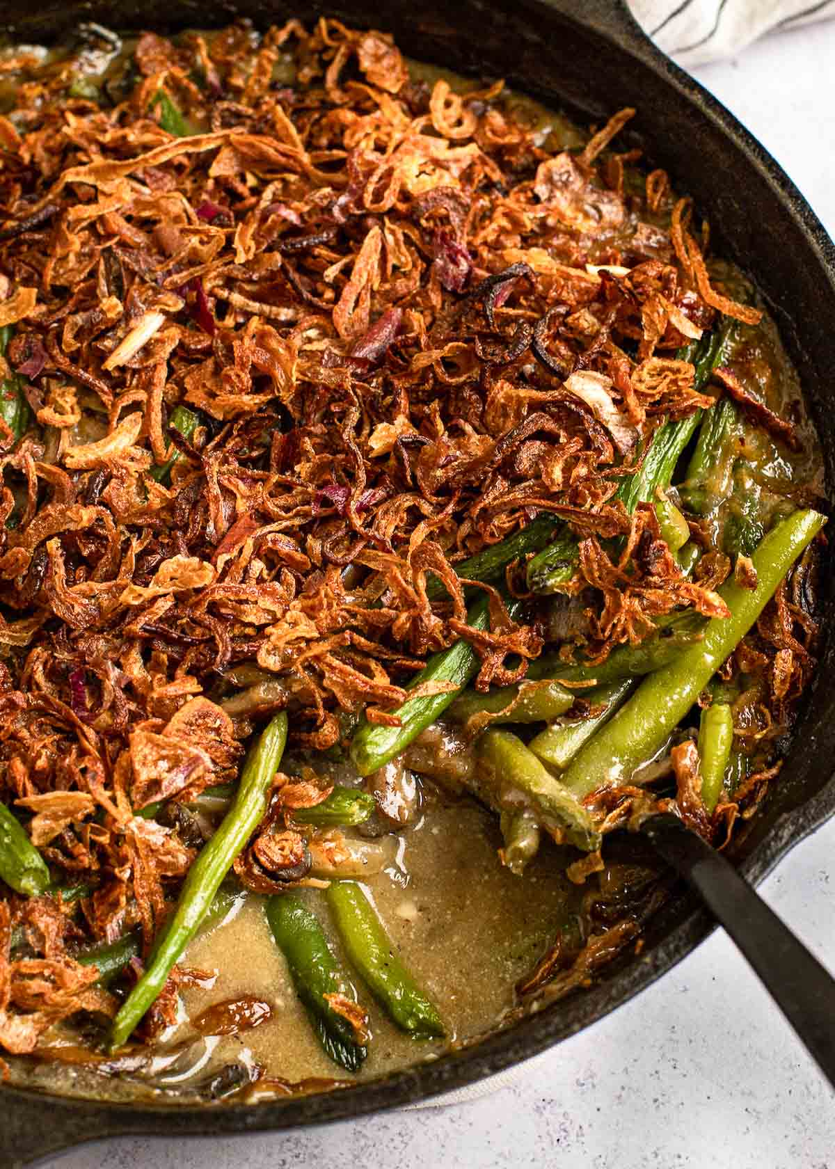 green bean casserole in a skillet with a serving spoon