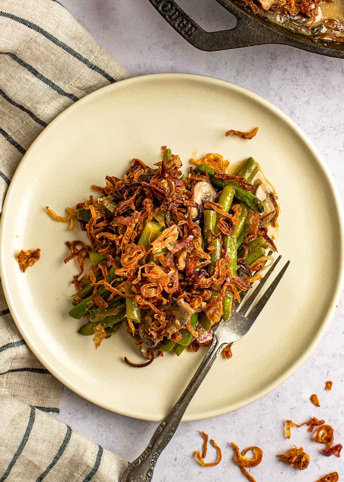 a plate full of homemade green bean casserole with crispy onions on top