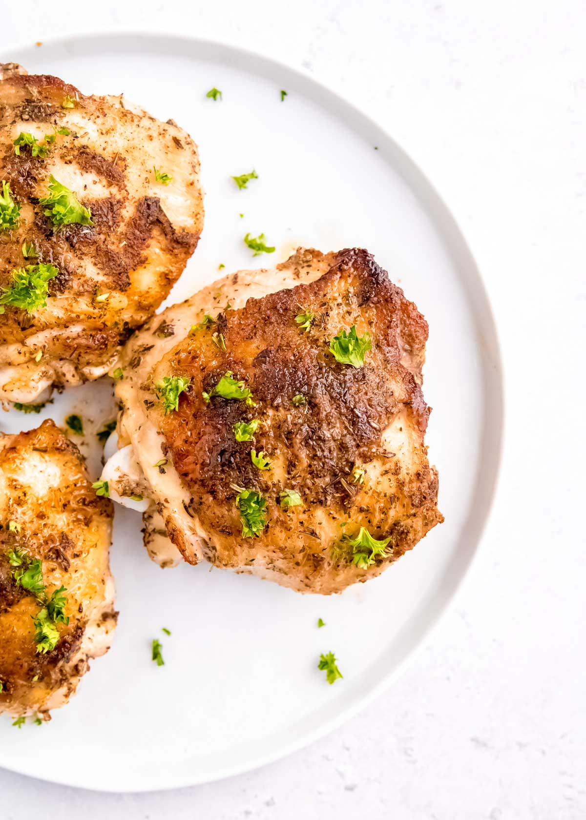 chicken thighs cooked on white plate with parsley