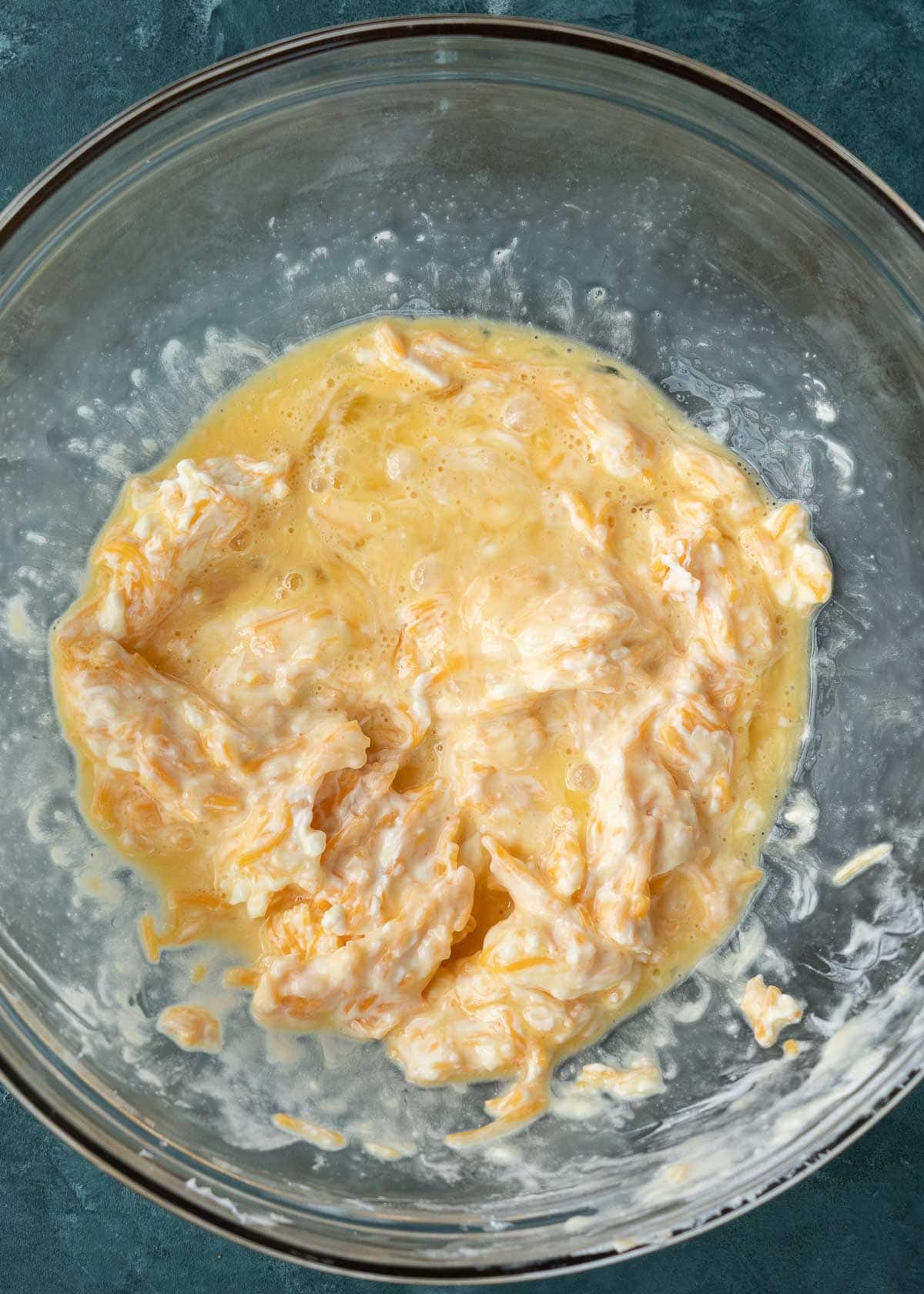 cream cheese, shredded cheese, heavy cream, and melted butter in a glass bowl