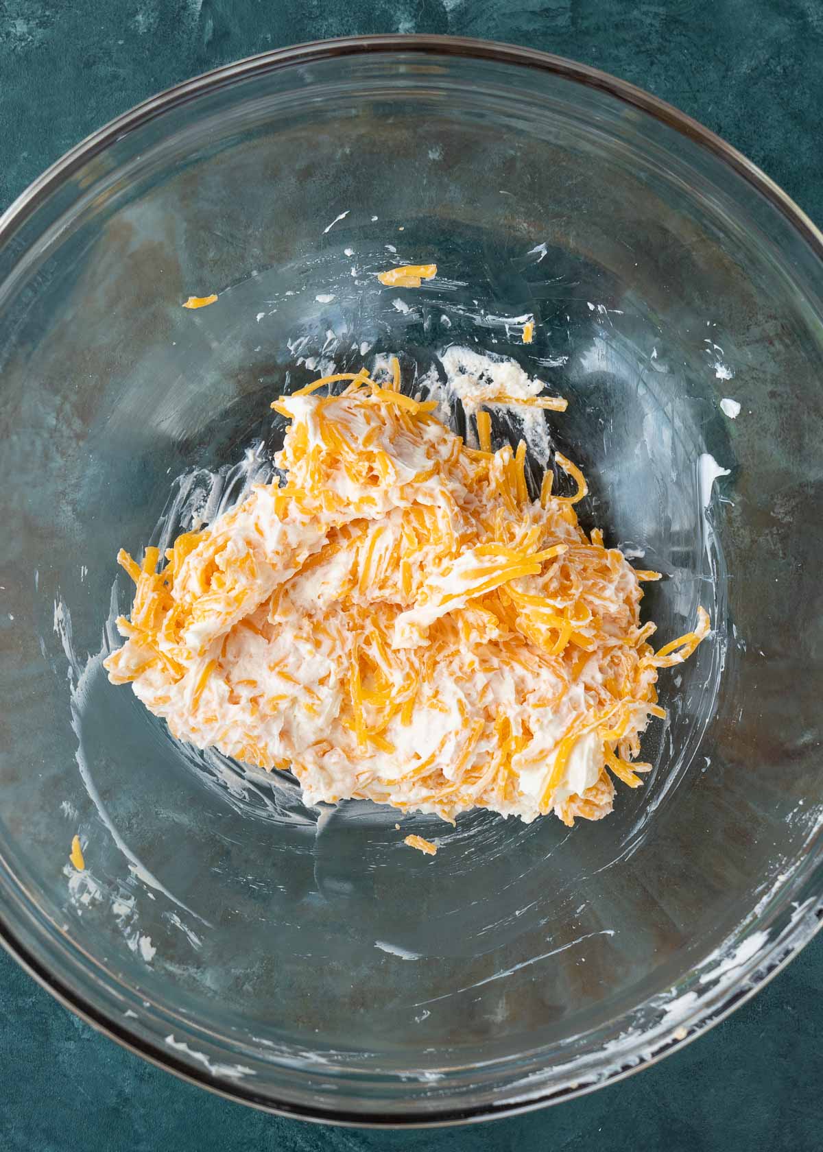 cream cheese and shredded cheese in a glass bowl