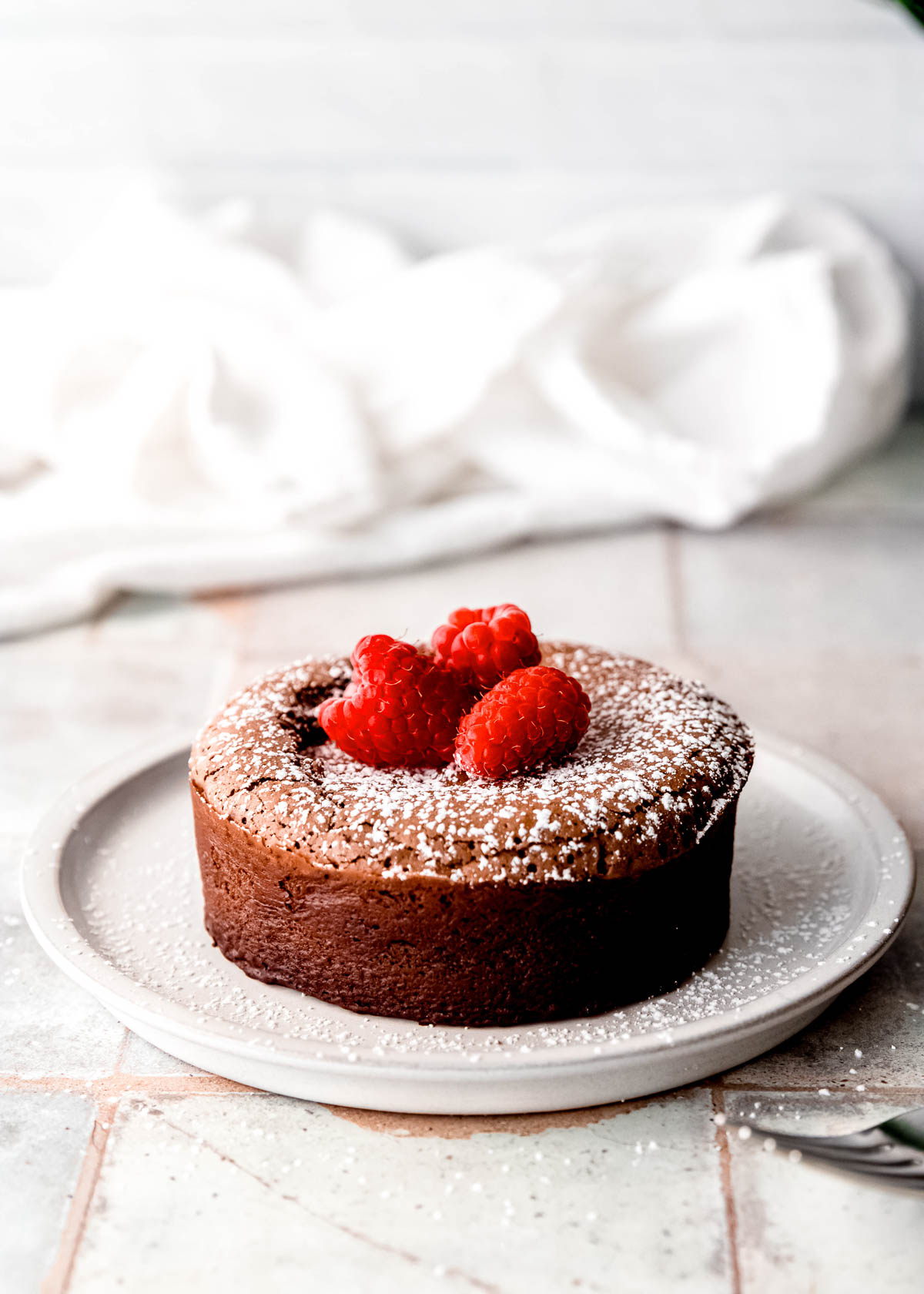 perfect molten lava cake on white plate, topped with fresh raspberries