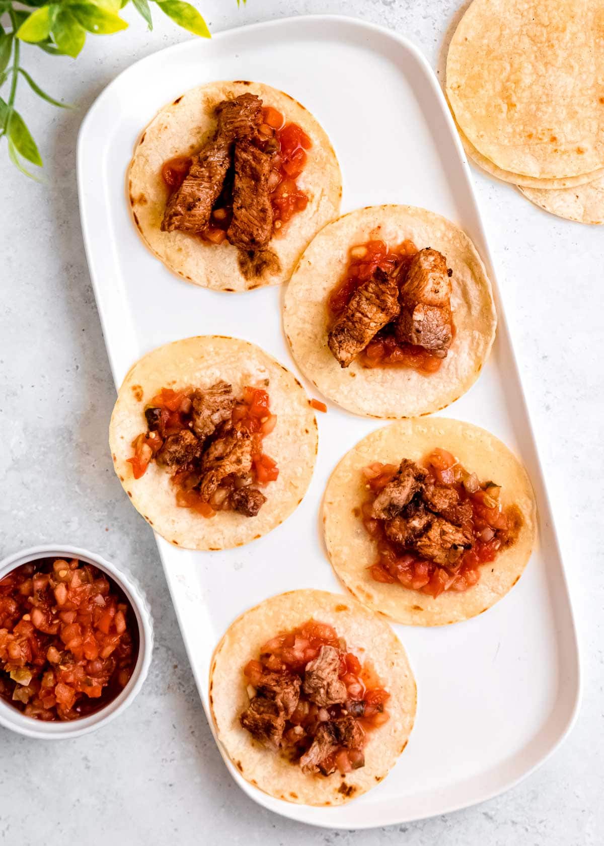 meat and peppers on tortilla on white platter