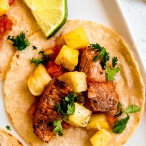 close up image of tacos al pastor on white background