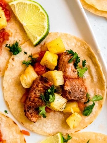 close up image of tacos al pastor on white background