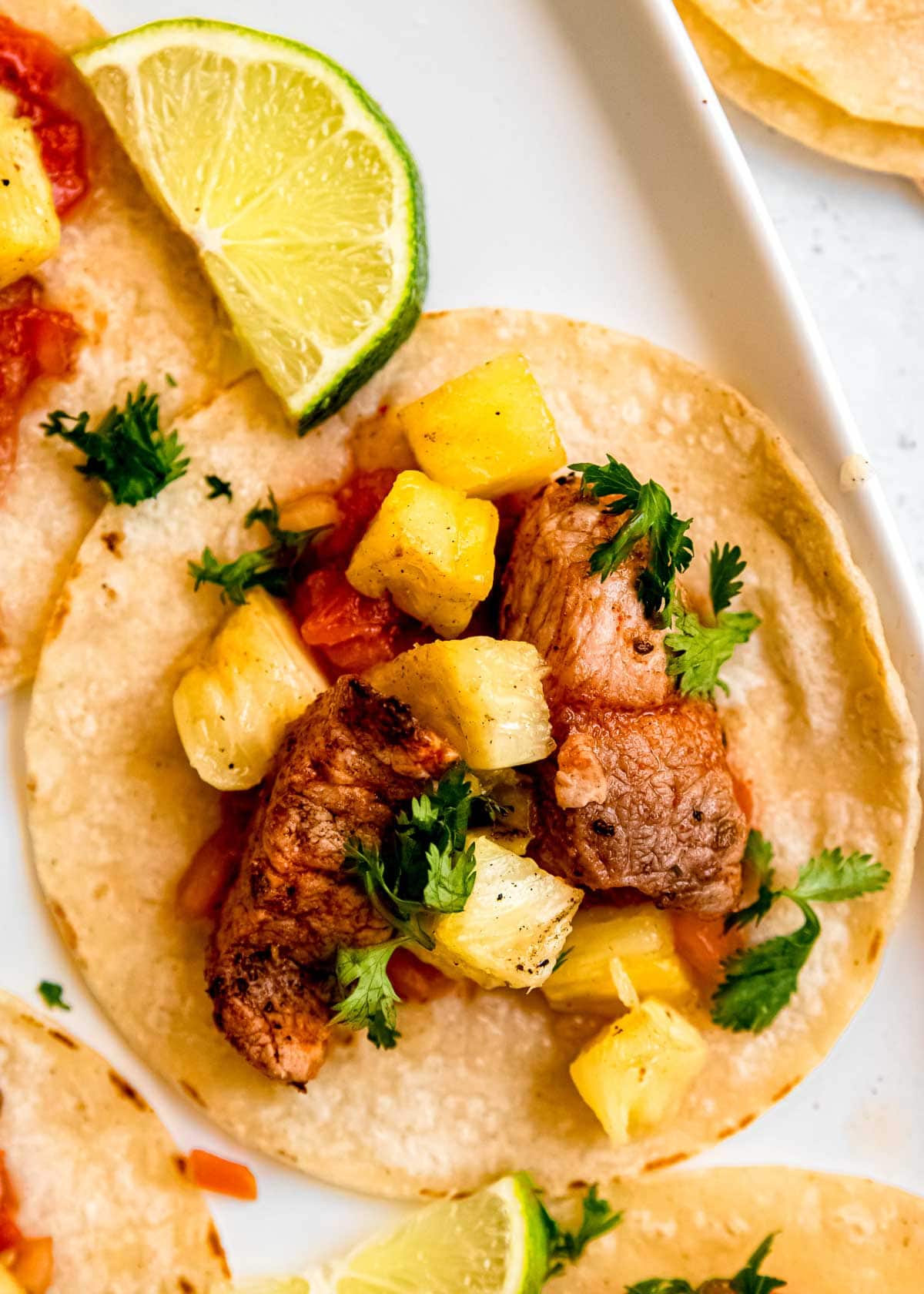 close up image of tacos al pastor on white background