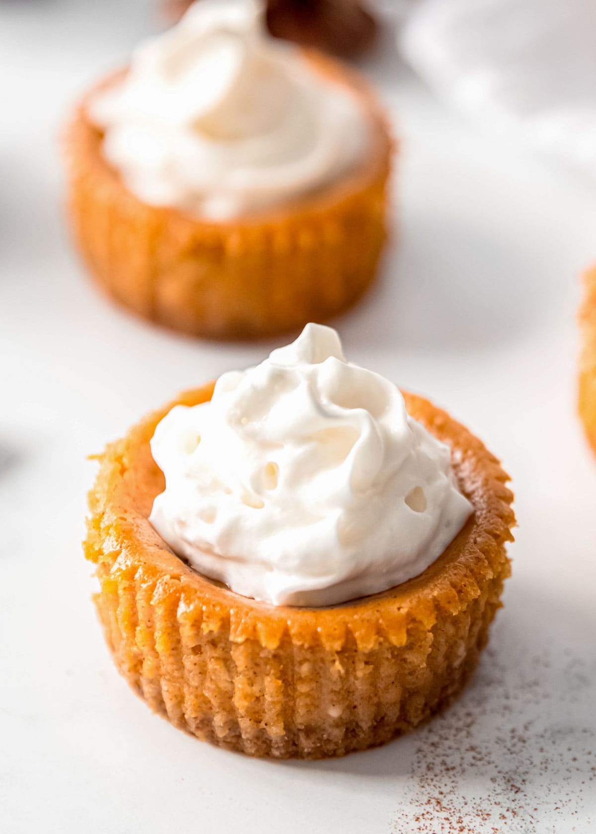 whipped cream on mini pumpkin cheesecakes