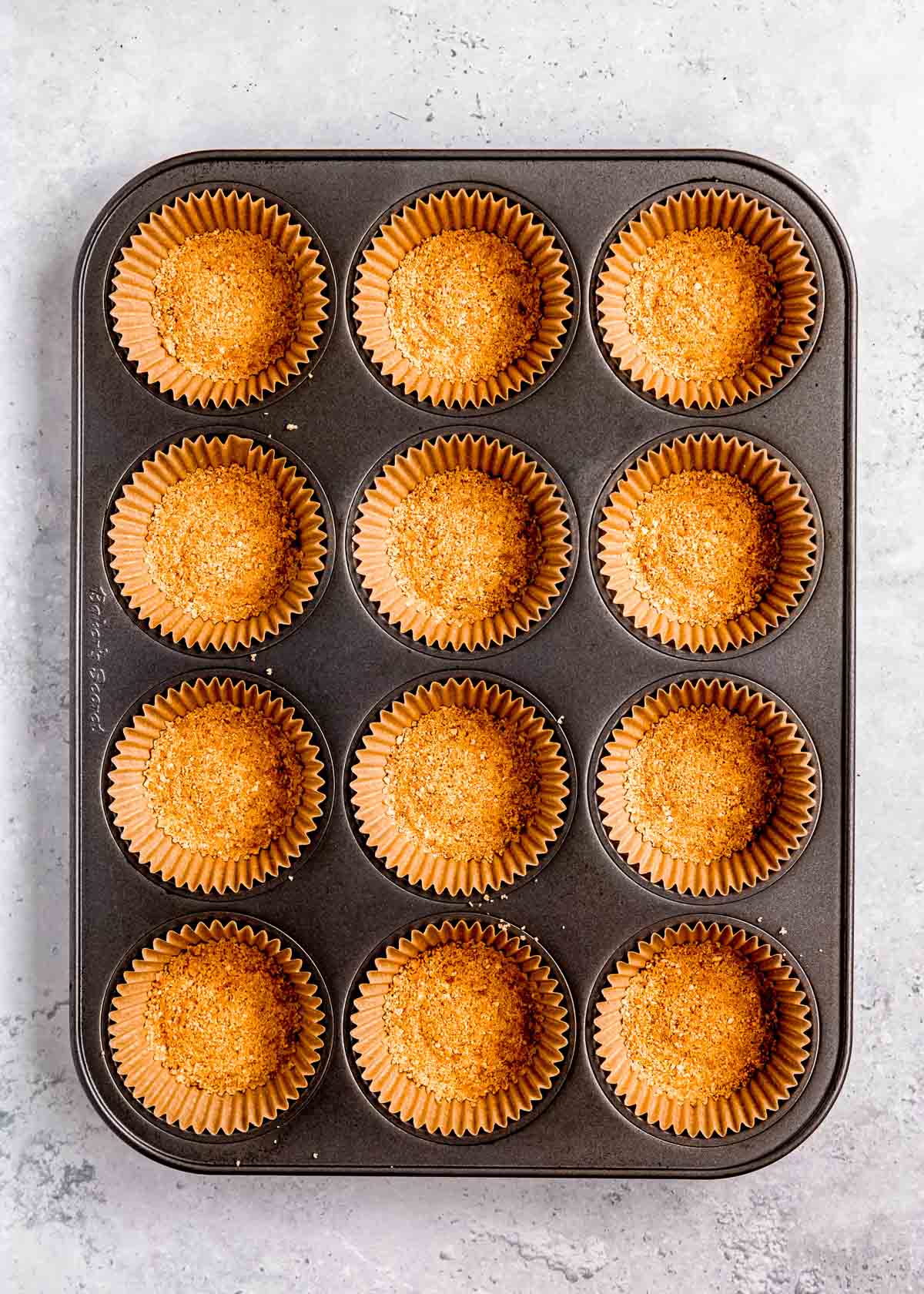 mini cheesecake crust in a muffin tin