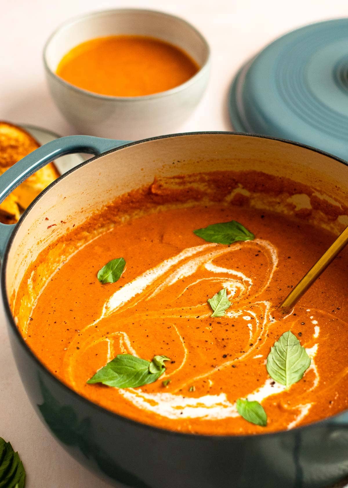 dutch oven with tomato soup with a drizzle of heavy cream and basil