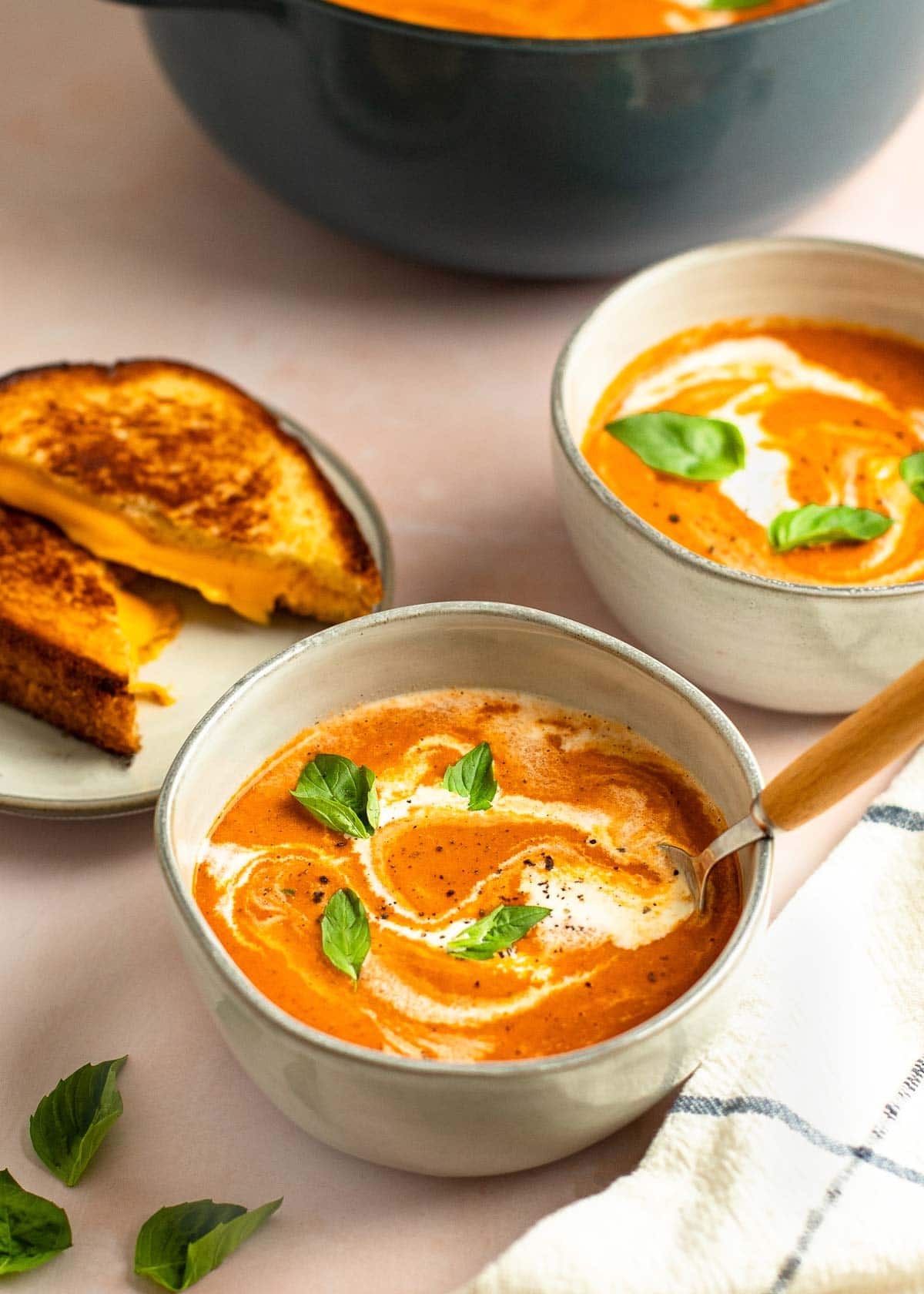 tomato soup in bowls with grilled cheese on side