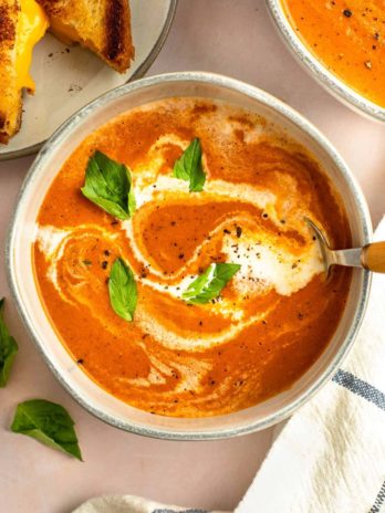 tomato soup in a bowl with a drizzle of heavy cream and basil