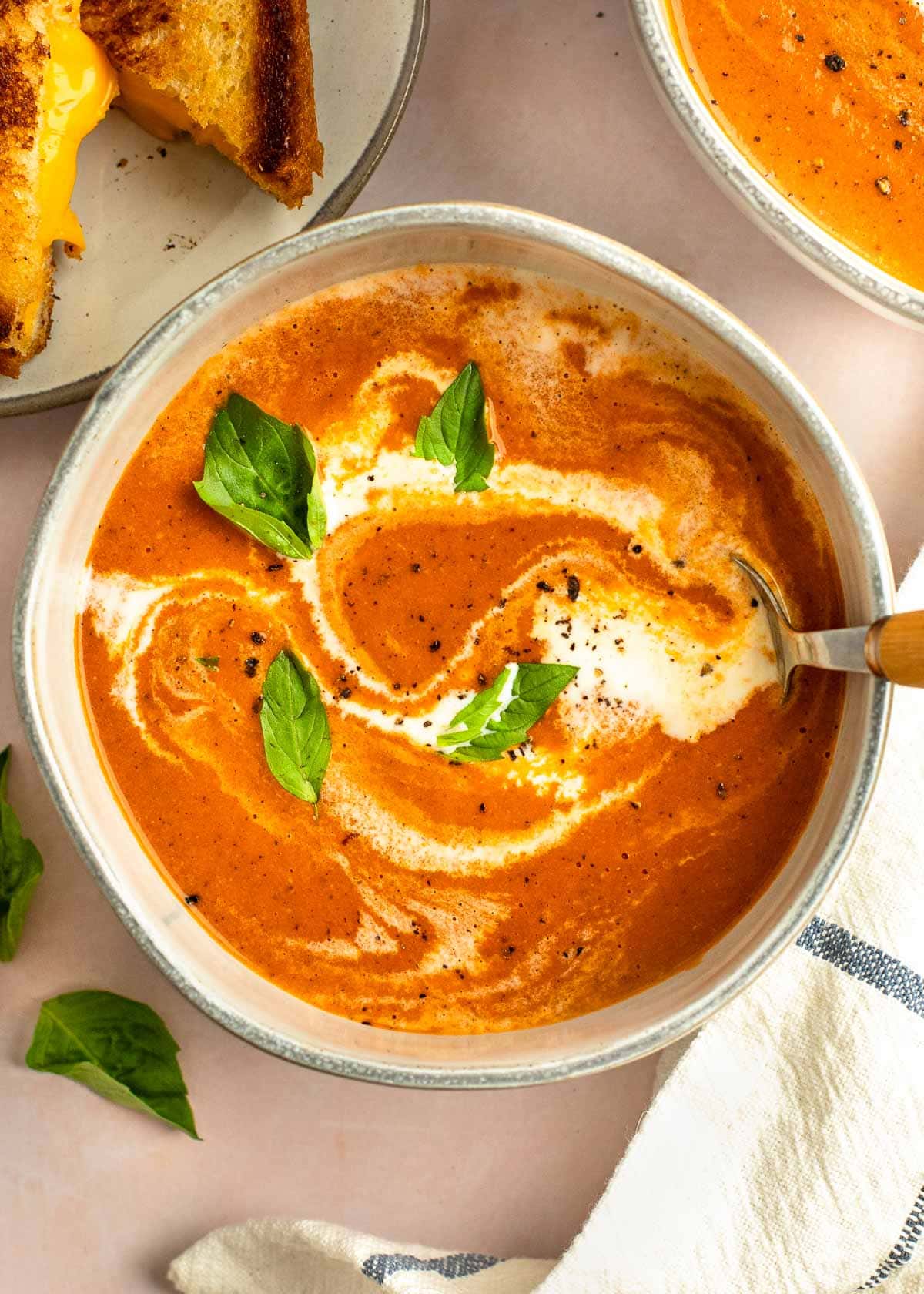 tomato soup in a bowl with a drizzle of heavy cream and basil