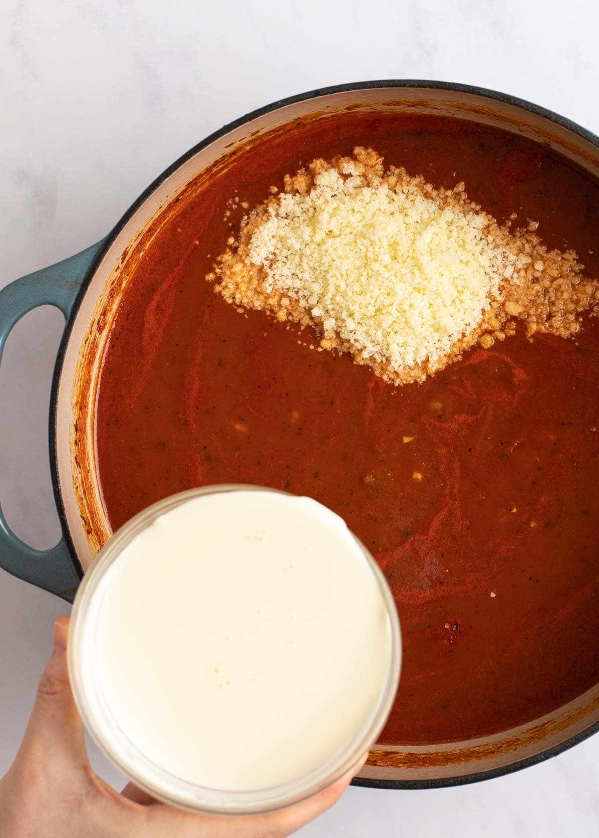 tomato soup ingredients in dutch oven with parmesan and heavy cream