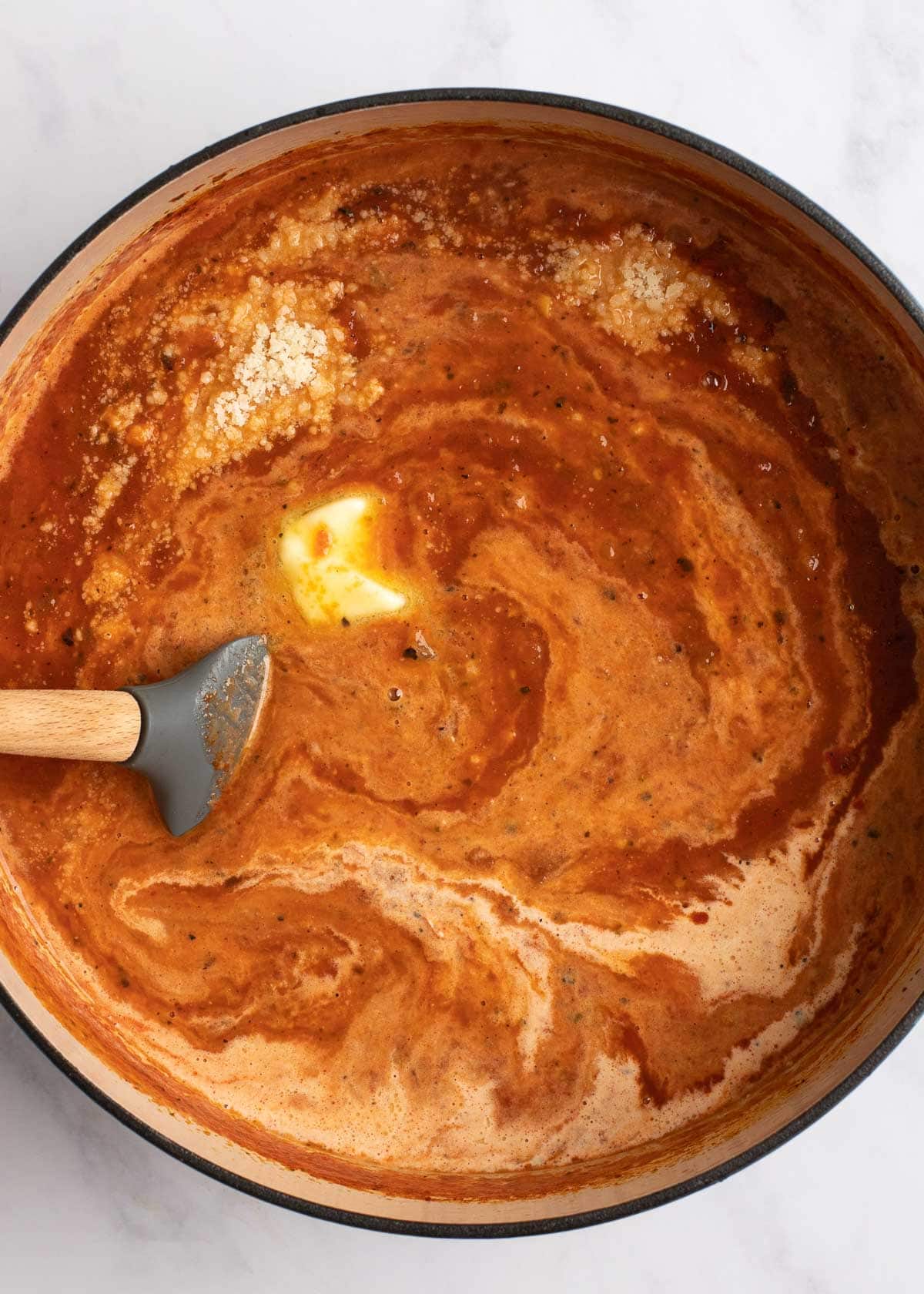 an overhead stir shot of creamy tomato soup