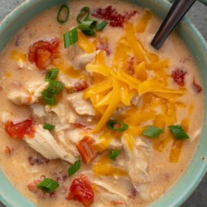 an overhead shot of chicken soup with cheese and rotel with a spoon
