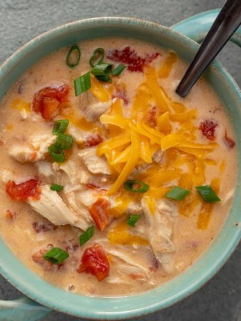 an overhead shot of chicken soup with cheese and rotel with a spoon